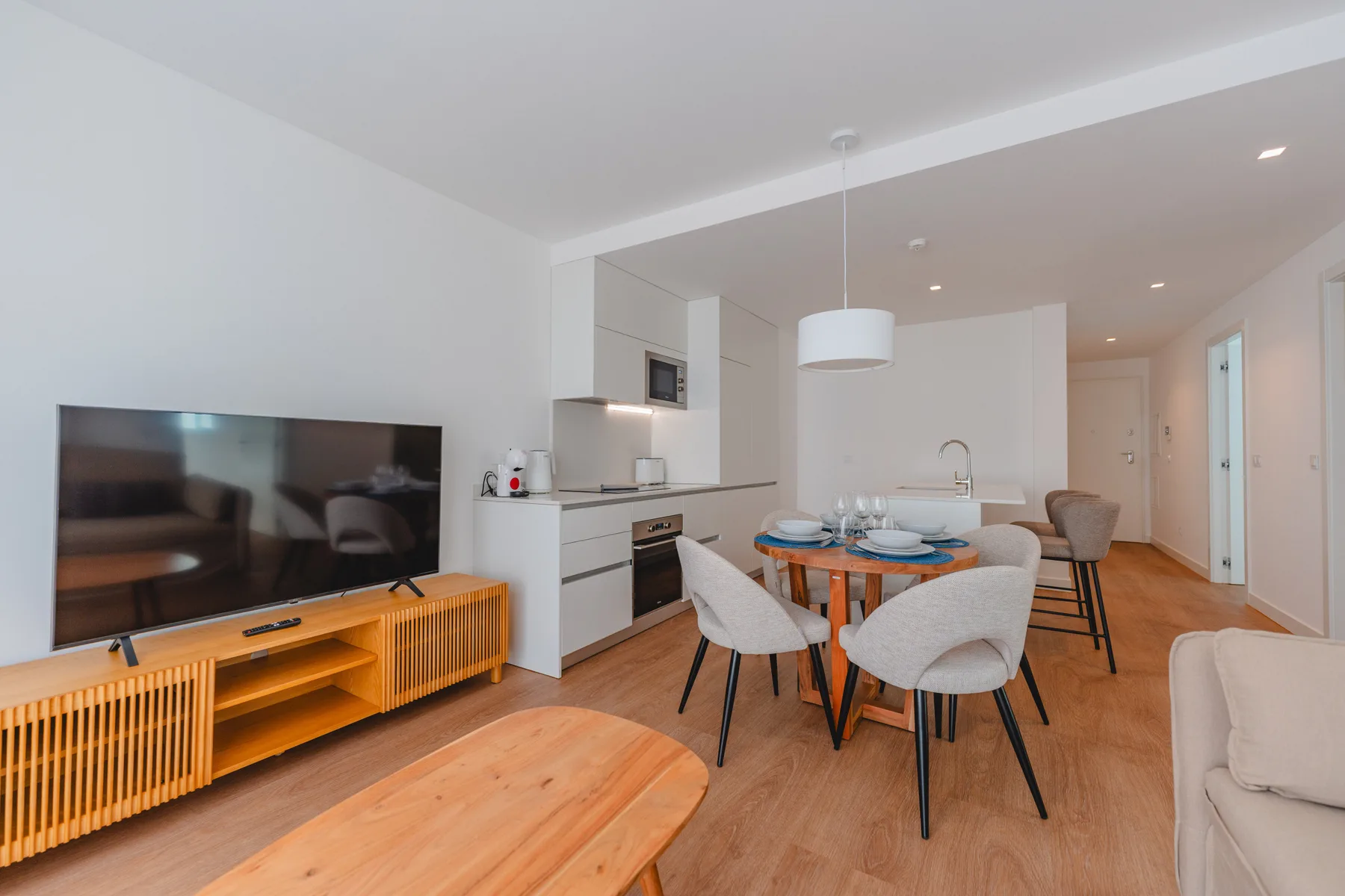 Una sala-comedor de planta abierta tiene un televisor, una mesa de comedor y una cocina.