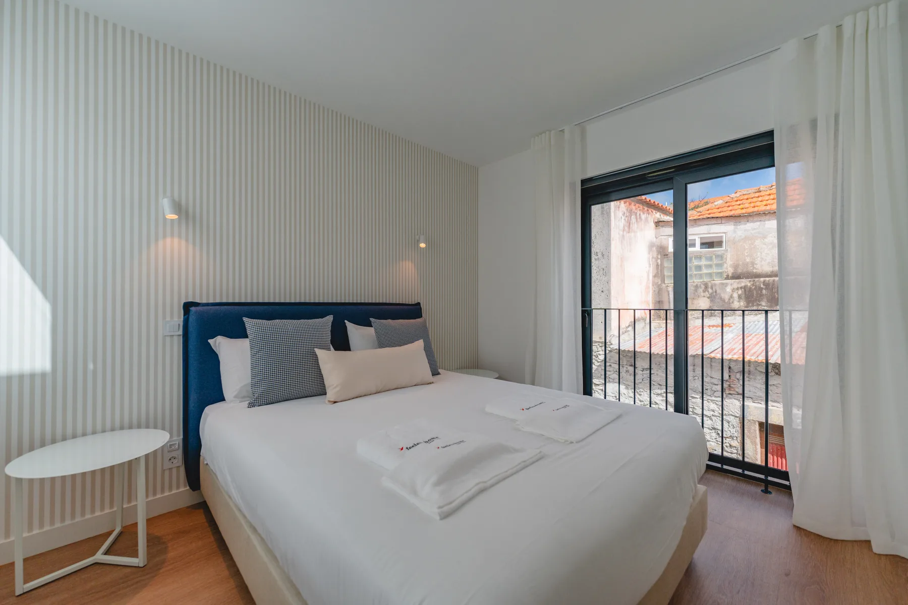 Dormitorio con una cama bien tendida junto a una ventana amplia.