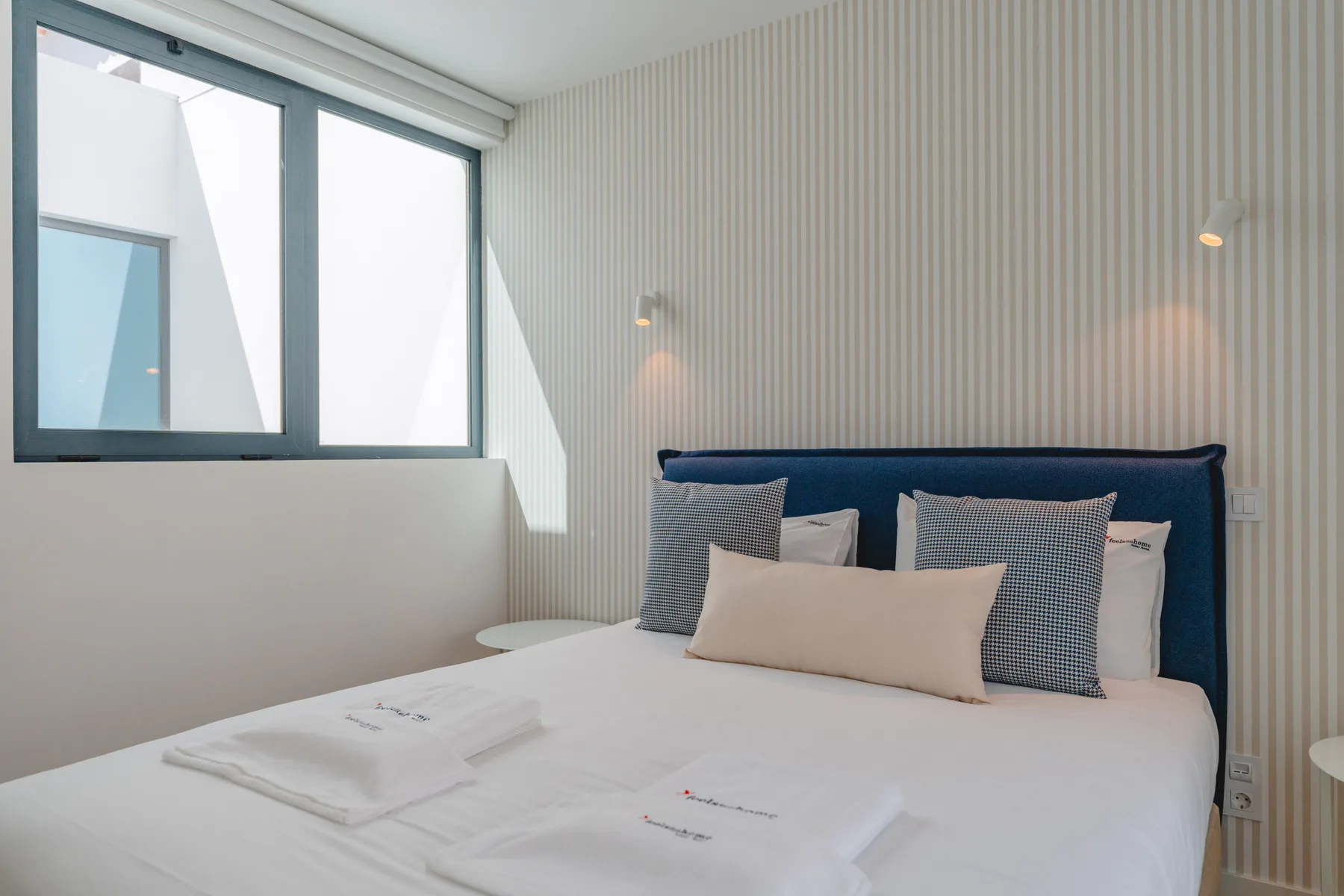 Un dormitorio con una cama grande y una ventana que da a una pared cercana.