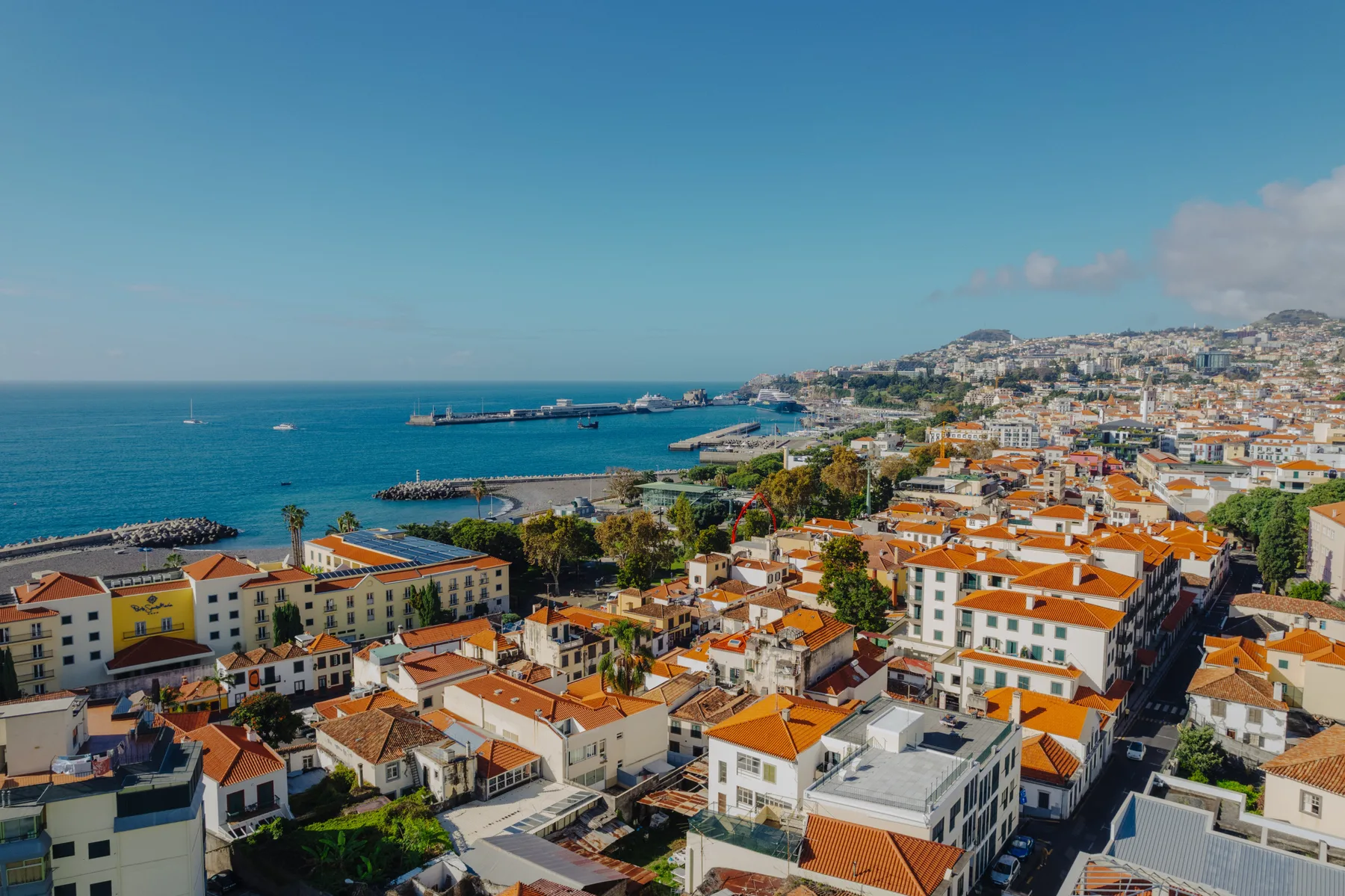 Paisaje urbano costero con edificios y tejados de tejas rojas junto al mar.