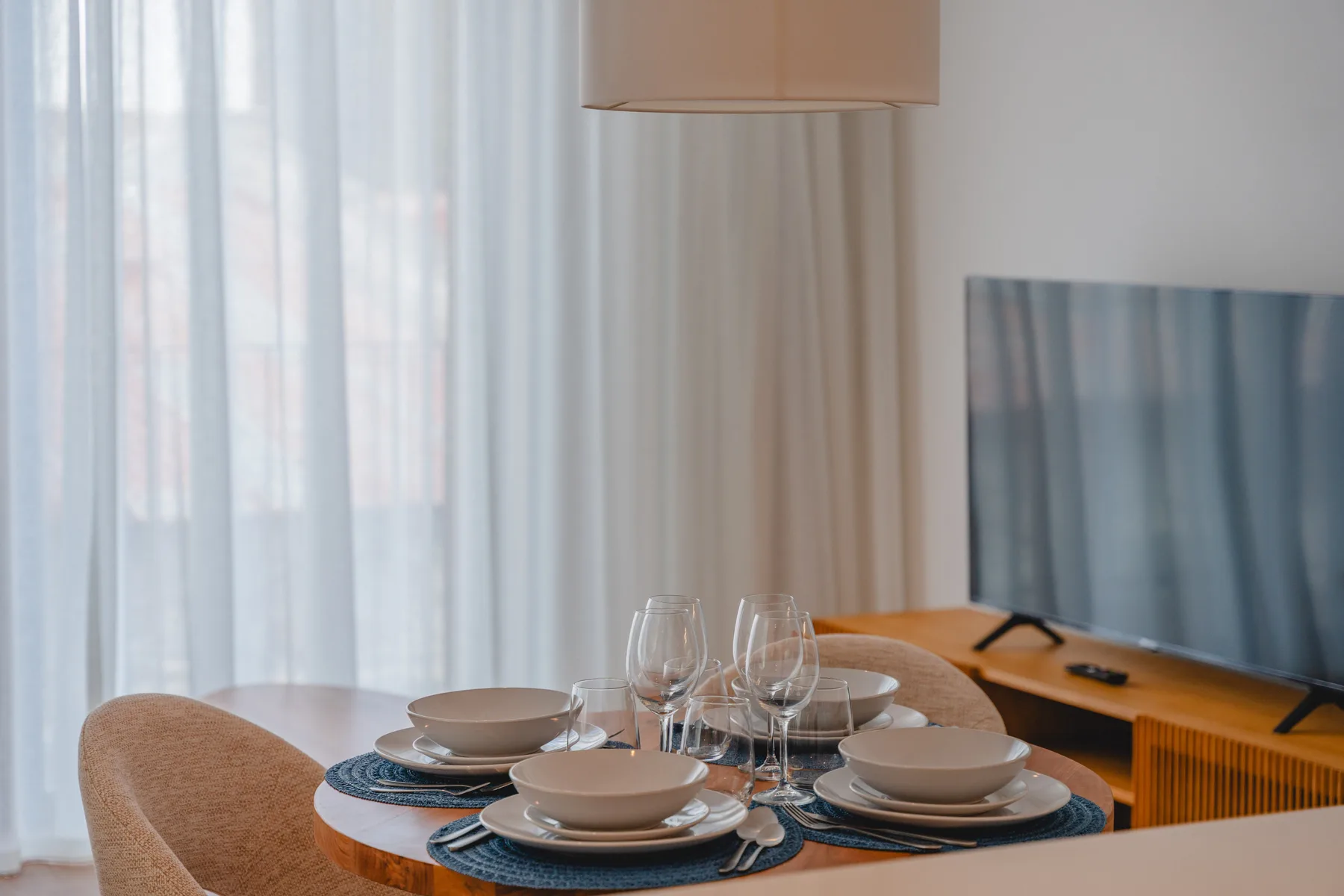 Comedor con la mesa puesta junto a un televisor.