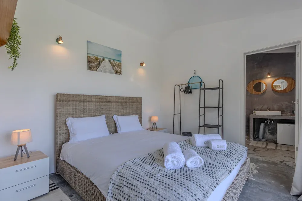 A bedroom with a double bed, bedside tables, and a patterned throw.