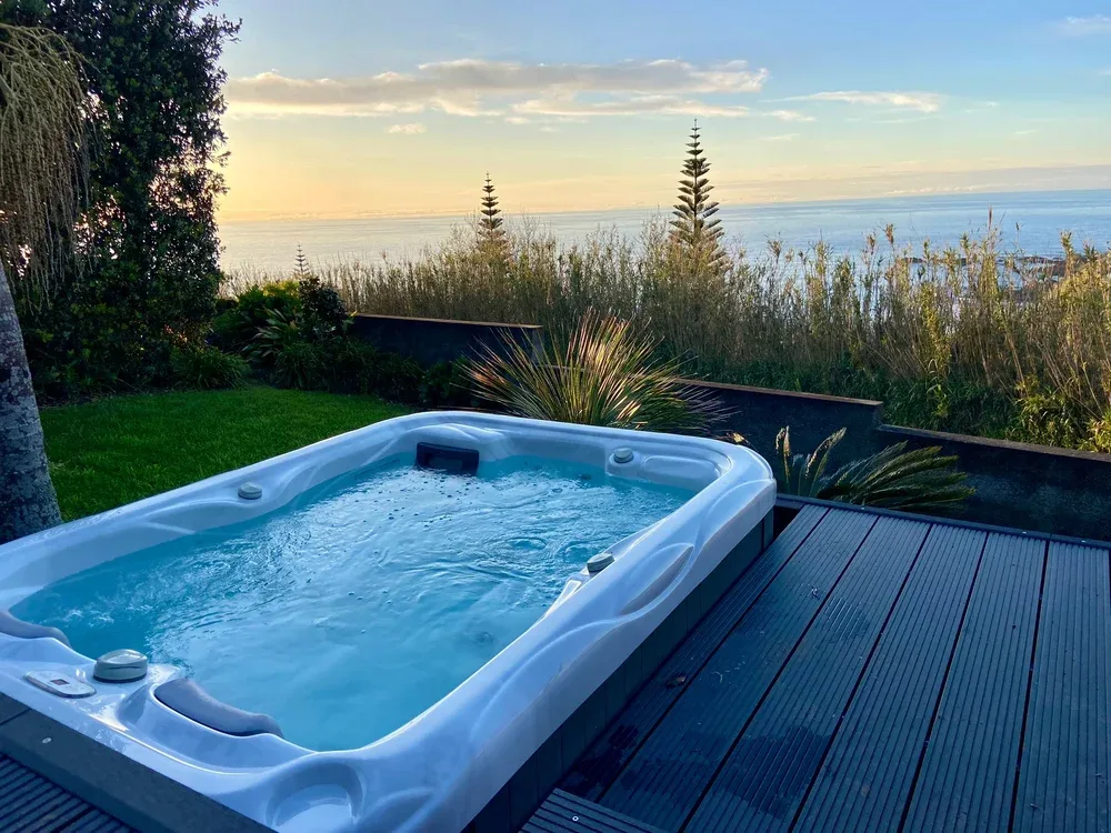 An outdoor hot tub sits on a deck overlooking the ocean.