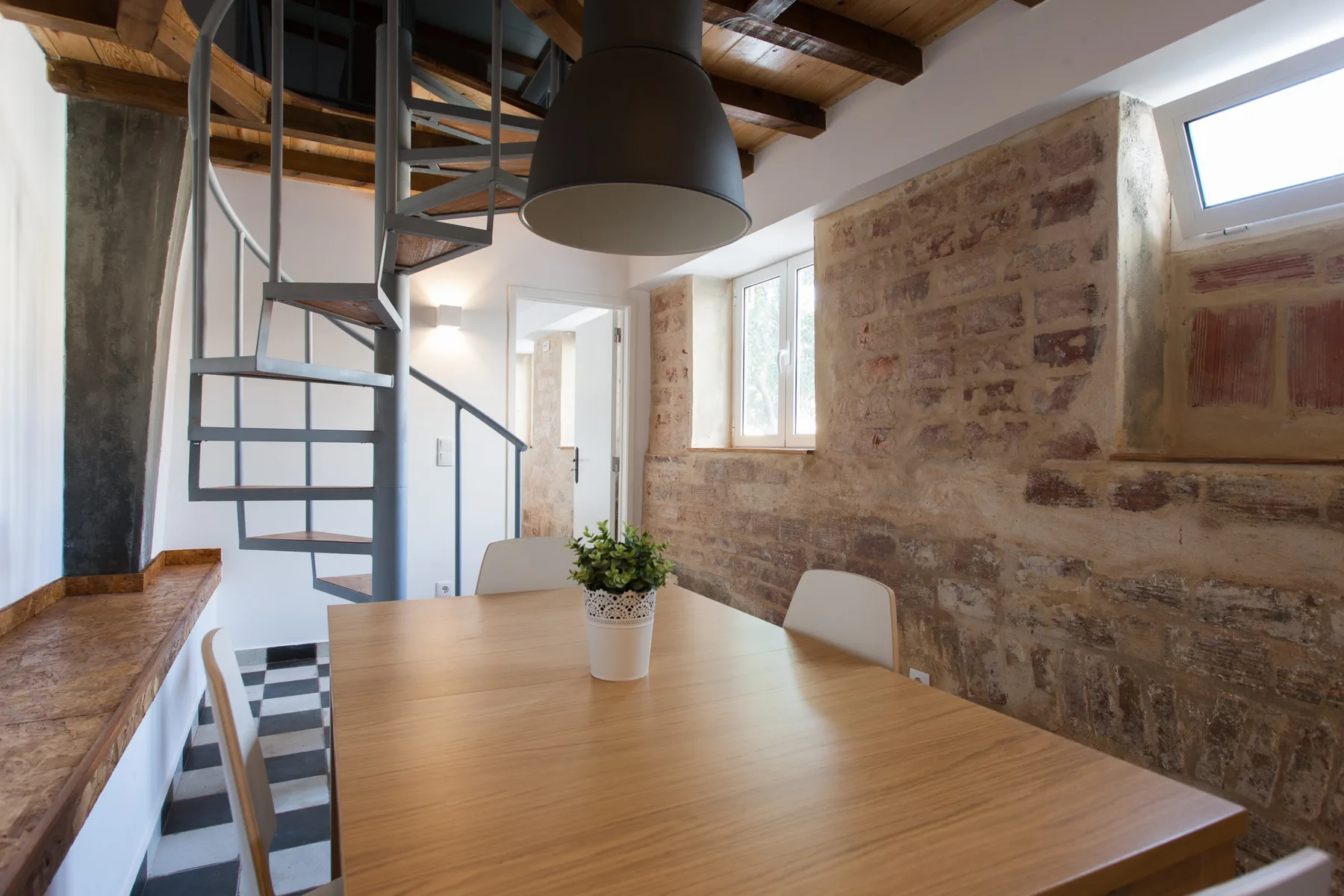 Comedor con una mesa de madera y una escalera de caracol.