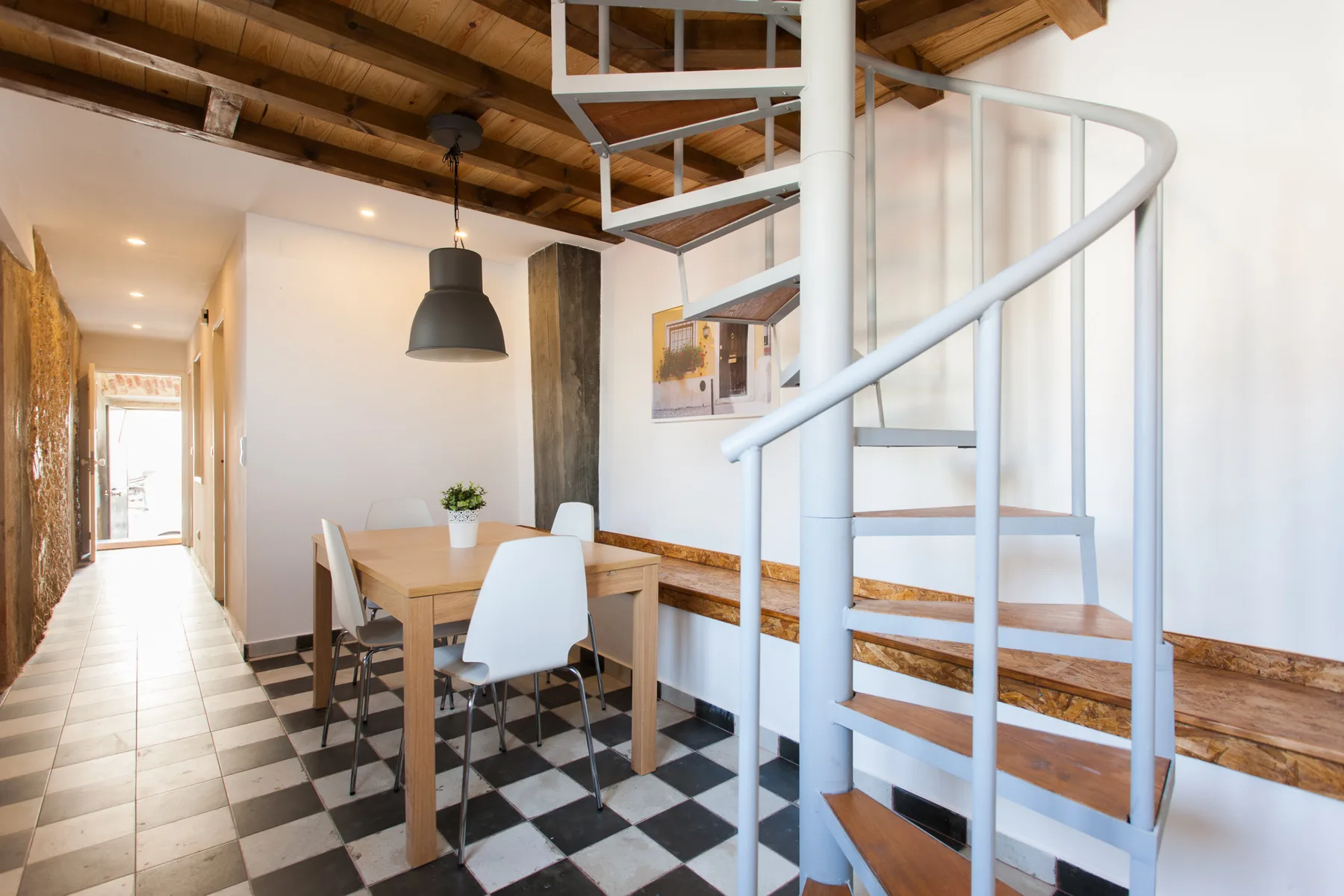 Comedor con una mesa y asientos junto a una escalera de caracol.