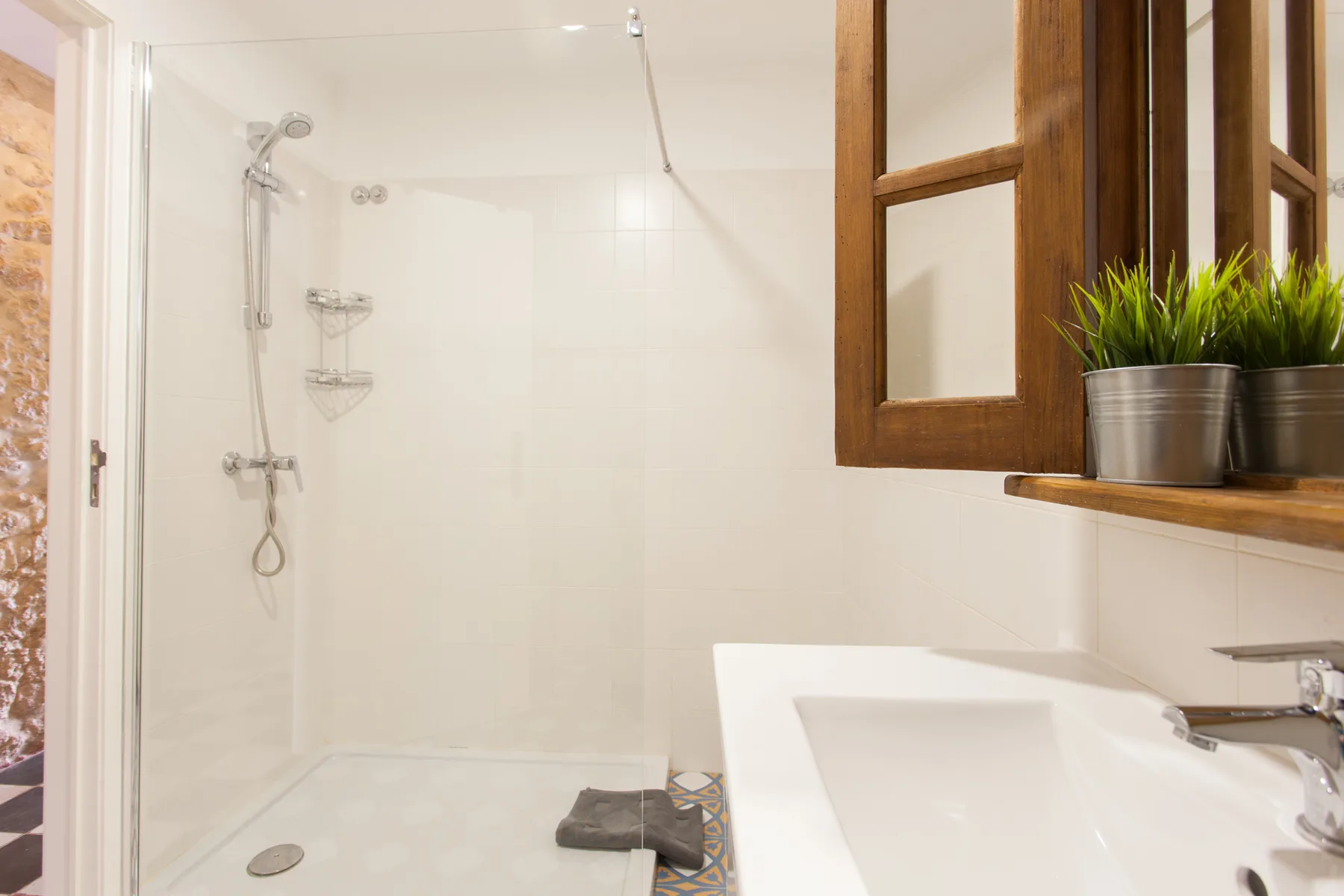 Un baño luminoso con una ducha y un lavabo blanco.