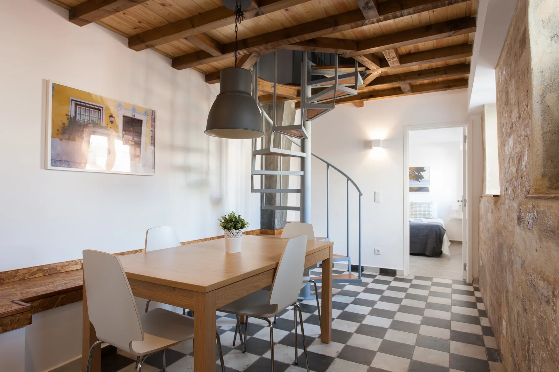 Un comedor con una mesa de madera está junto a una escalera de caracol.