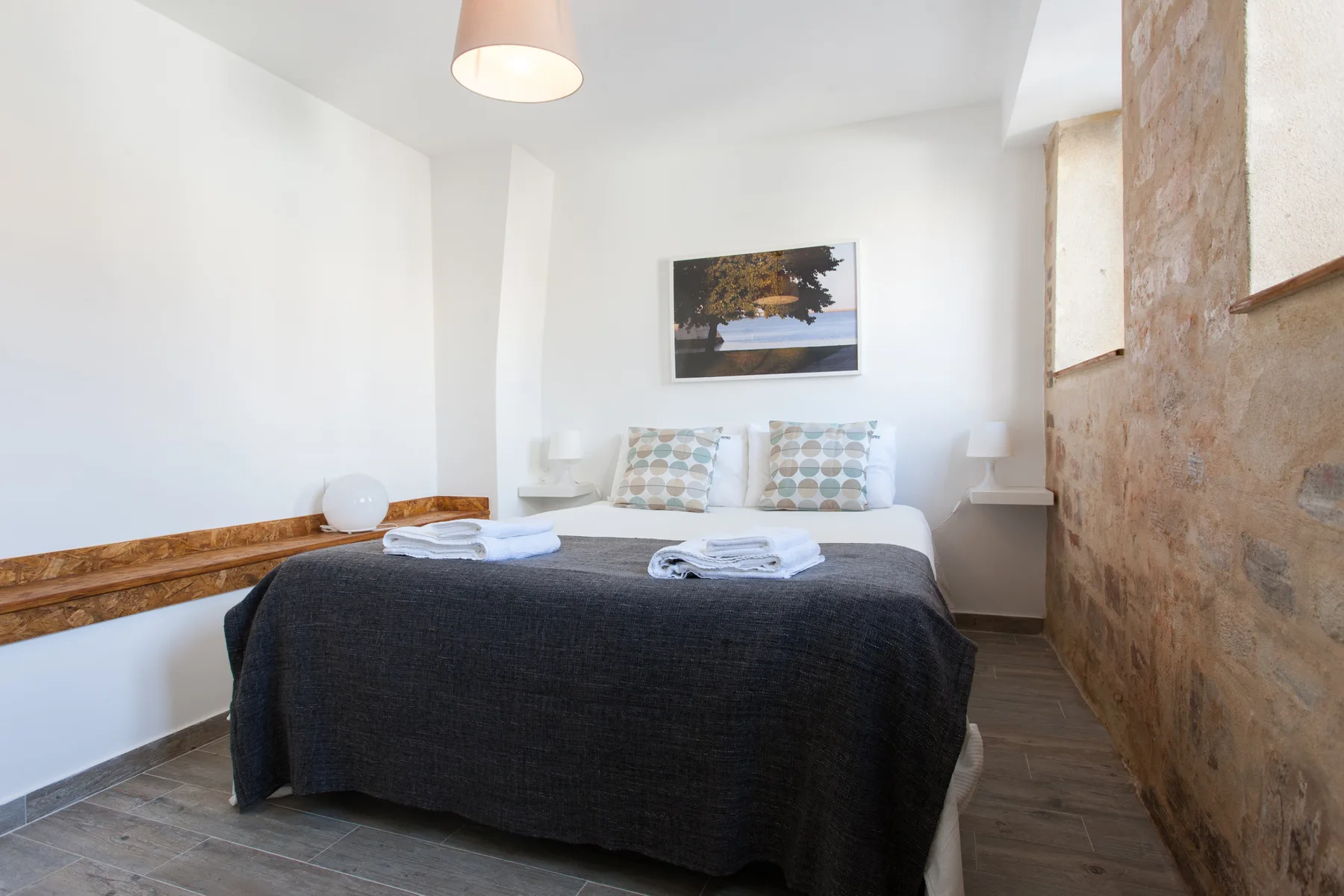 Un dormitorio con una cama doble, almohadas estampadas y un cuadro enmarcado encima.