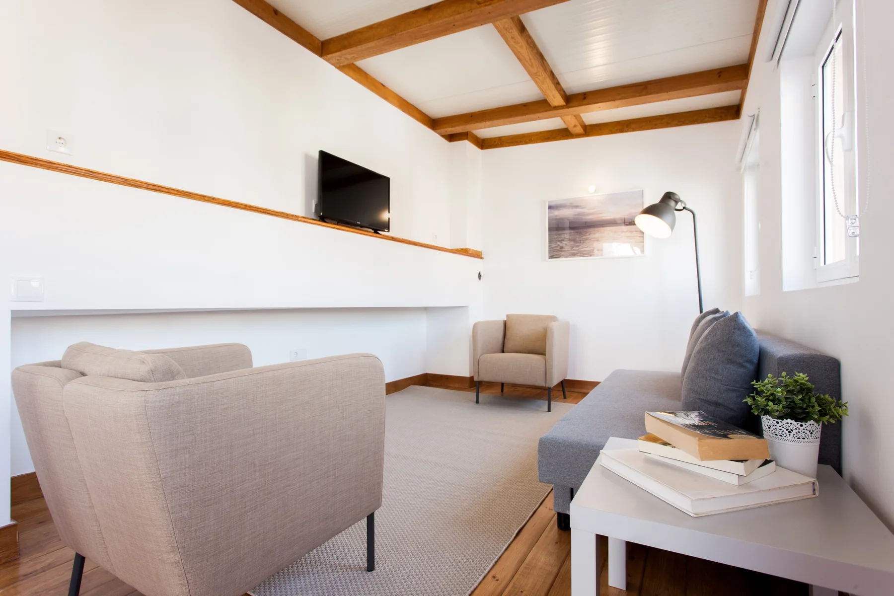 Una sala luminosa con asientos, un televisor y una lámpara de pie.