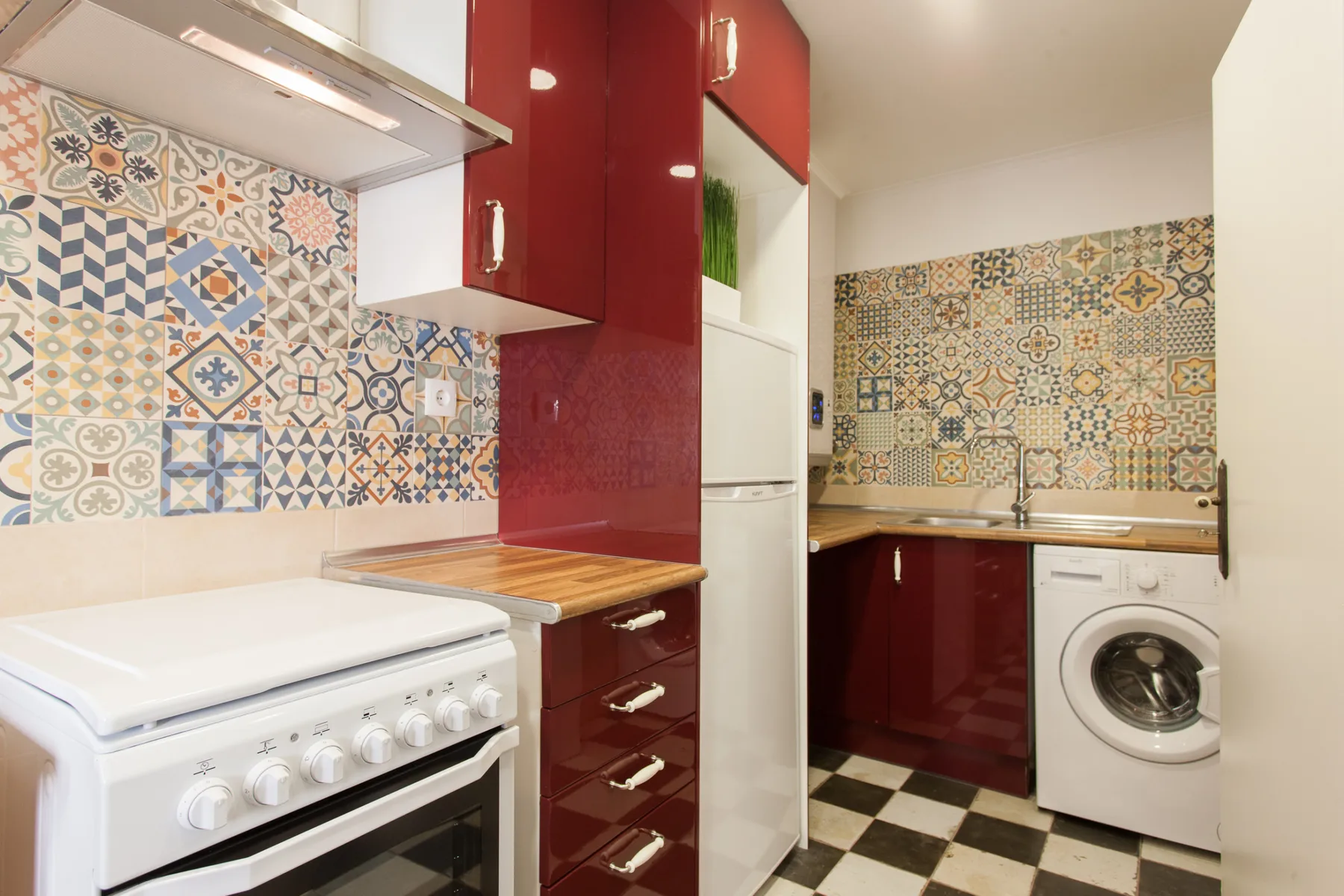 Una cocina con paredes de azulejos estampados y una lavadora.