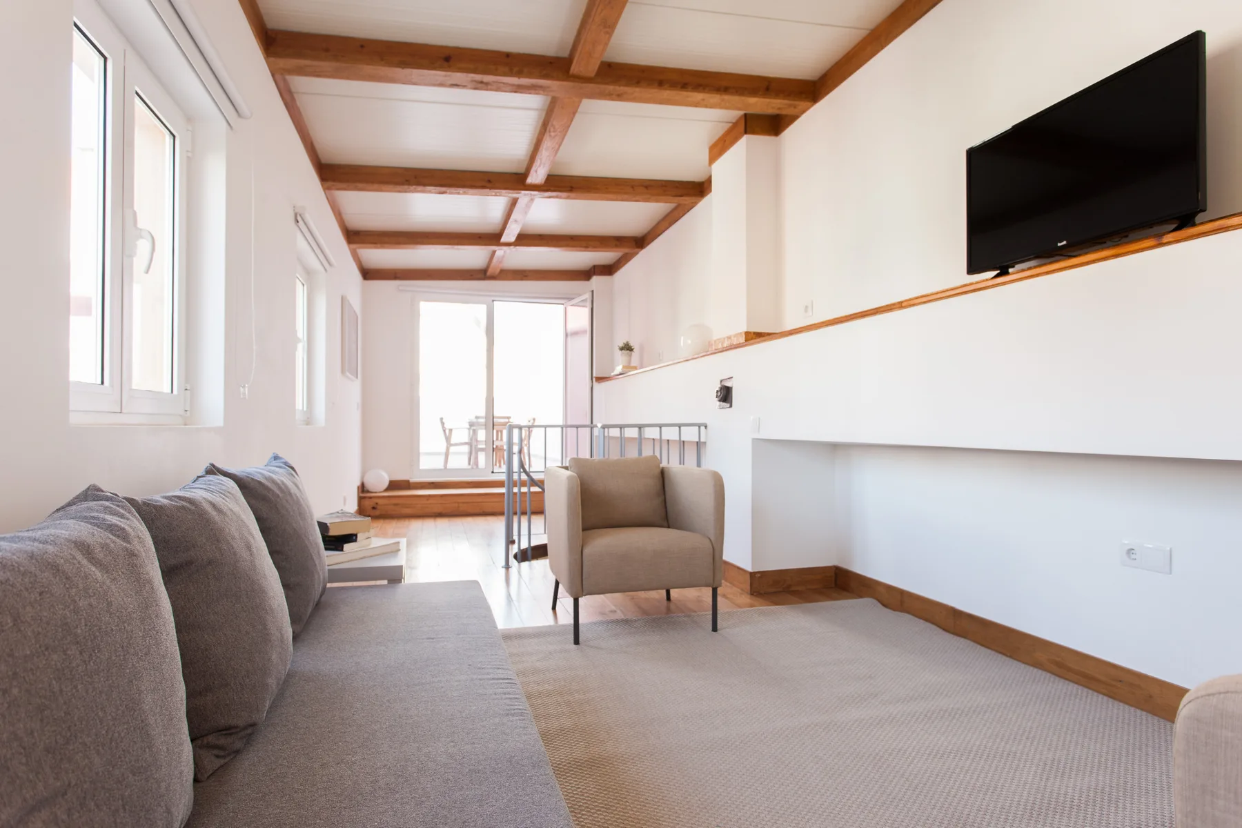 Una sala luminosa con asientos bajo vigas de madera a la vista.