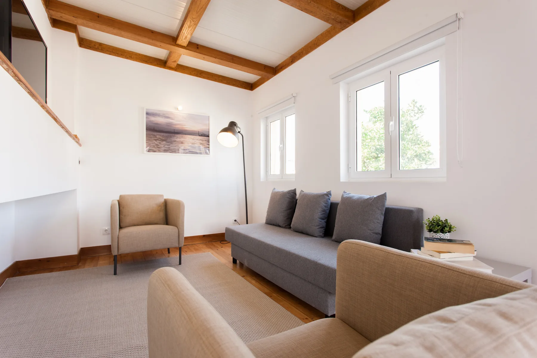Una sala luminosa con asientos, ventanas amplias y vigas de techo expuestas.