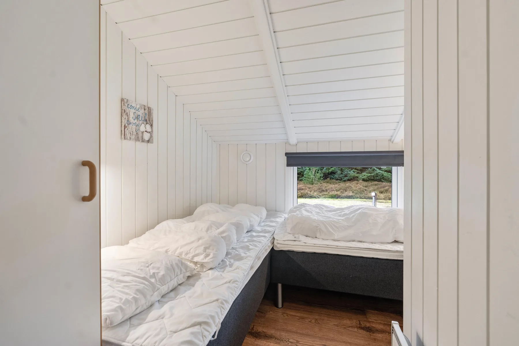 Una zona compacta para dormir con camas bajo un techo blanco inclinado.