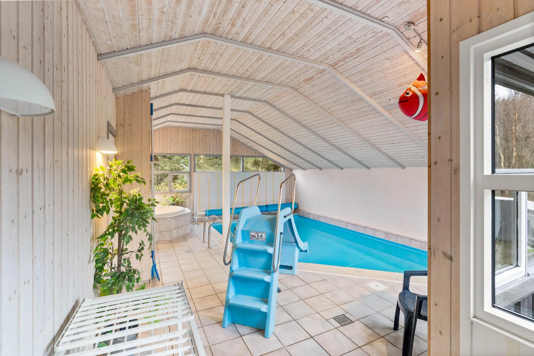 Una piscina cubierta con un tobogán azul y suelo de baldosas.