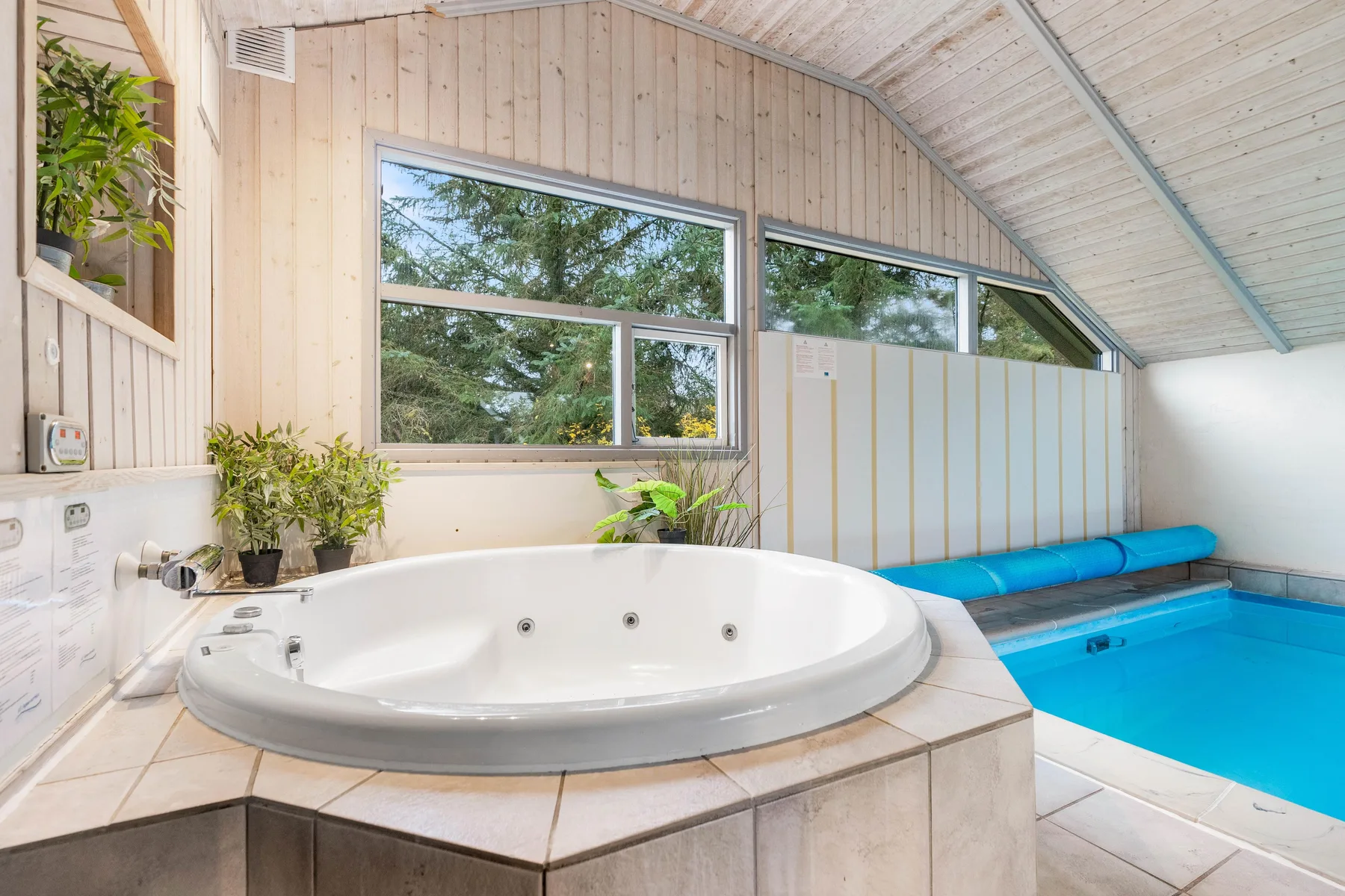 Una zona de piscina cubierta cuenta con una bañera de hidromasaje junto a la piscina.