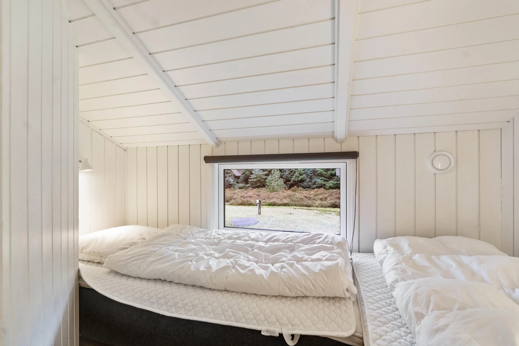 Un dormitorio con dos camas bajo un techo blanco inclinado.