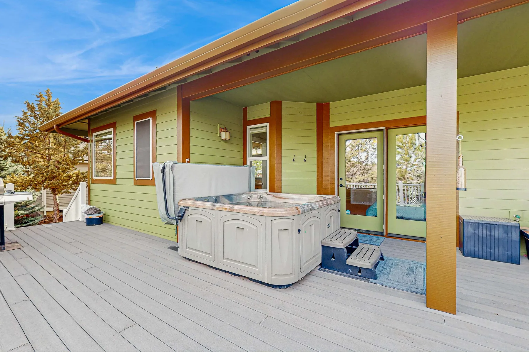 Una terraza exterior cubierta con una bañera de hidromasaje junto a la casa.