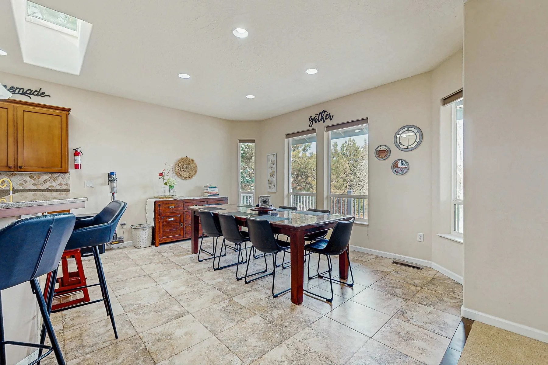 A dining area with a long table and chairs beside the kitchen counter.