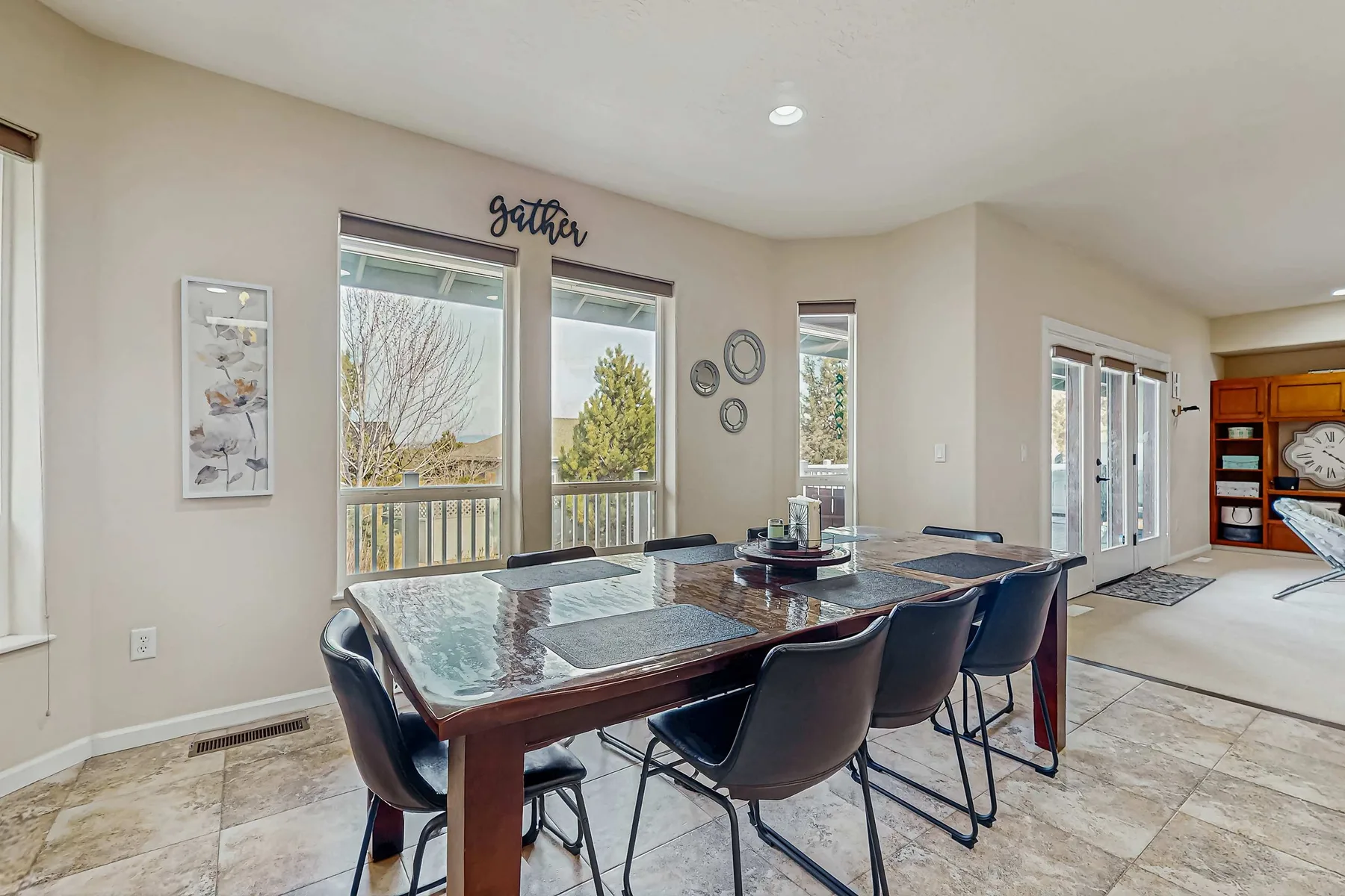 A dining area with a rectangular table and large windows.