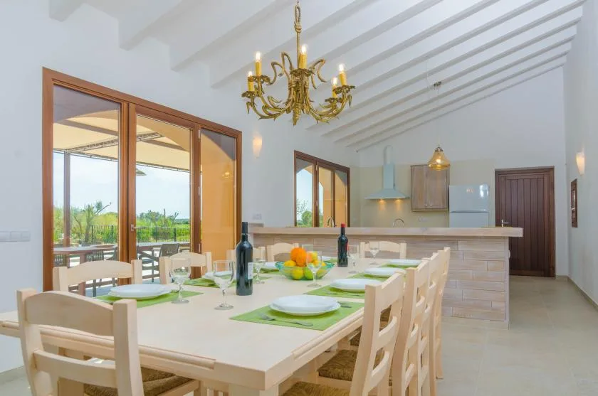 A bright dining area with a long table set beside large glass doors.