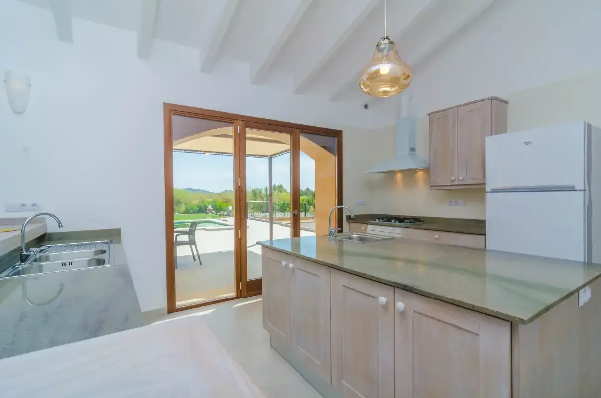 A bright kitchen with a countertop and glass doors opening onto an outdoor patio.