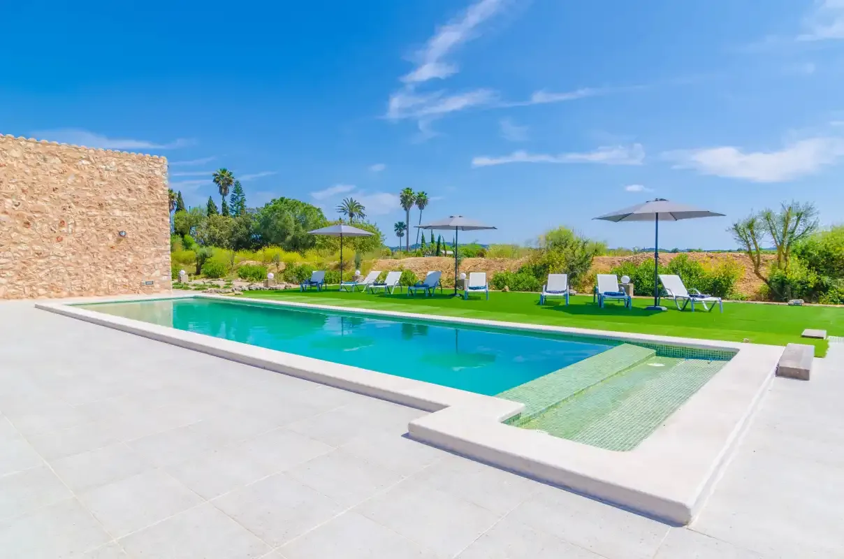 An outdoor swimming pool with a shallow section beside a lawn.