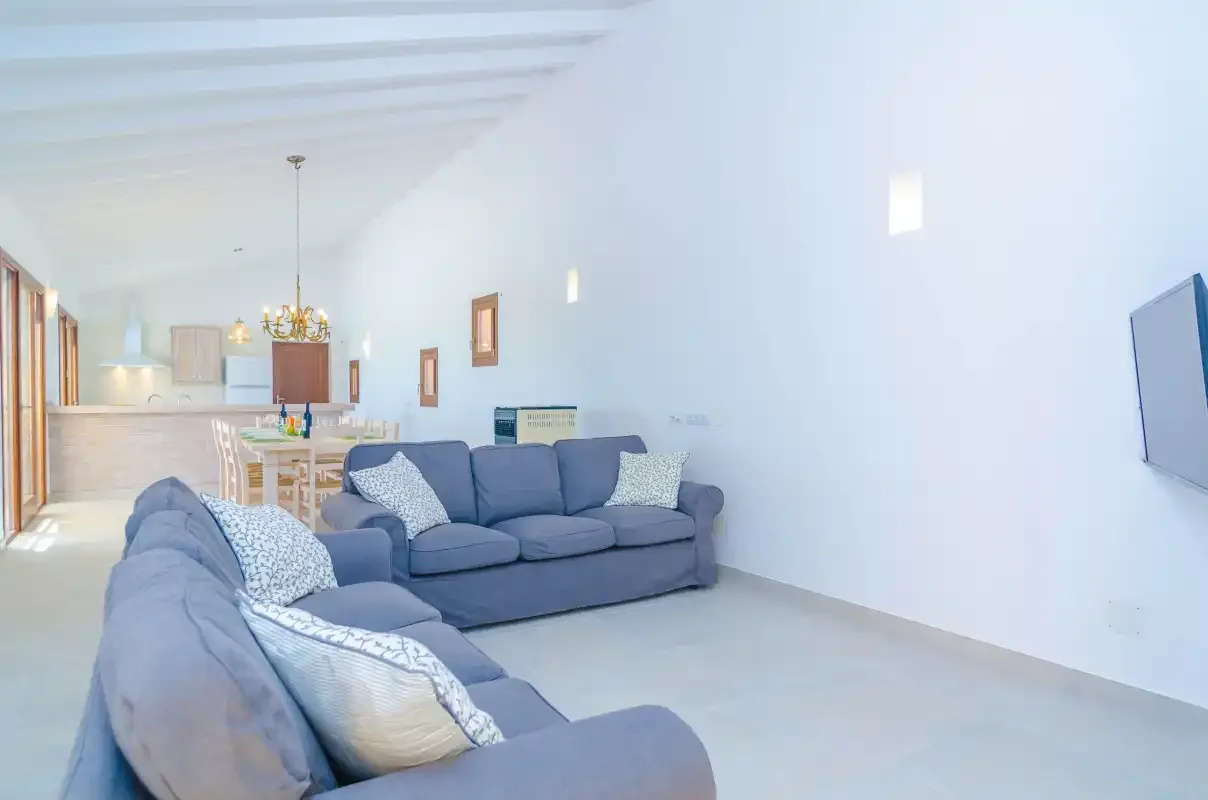 A bright living room with gray seating and a dining area in the background.