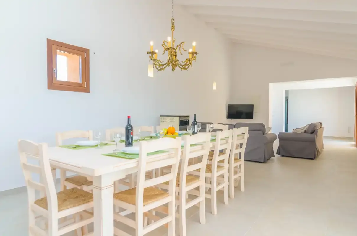 A dining area with a long table and chairs beside a living area.