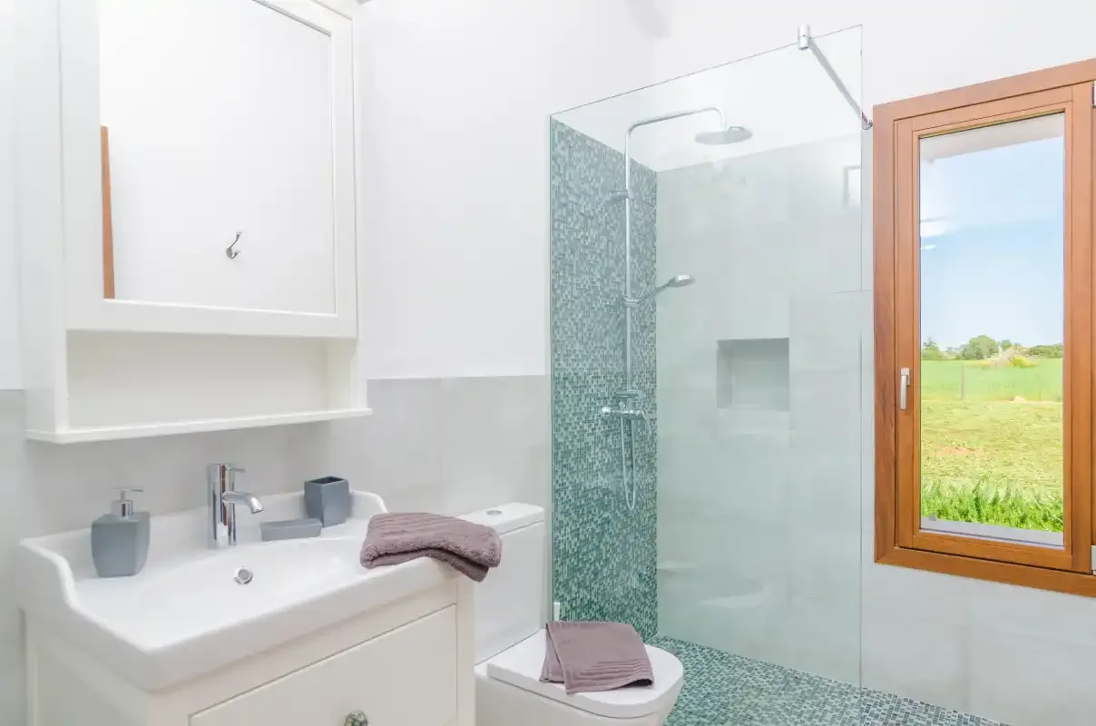 A bright bathroom with a sink, toilet, and glass shower.
