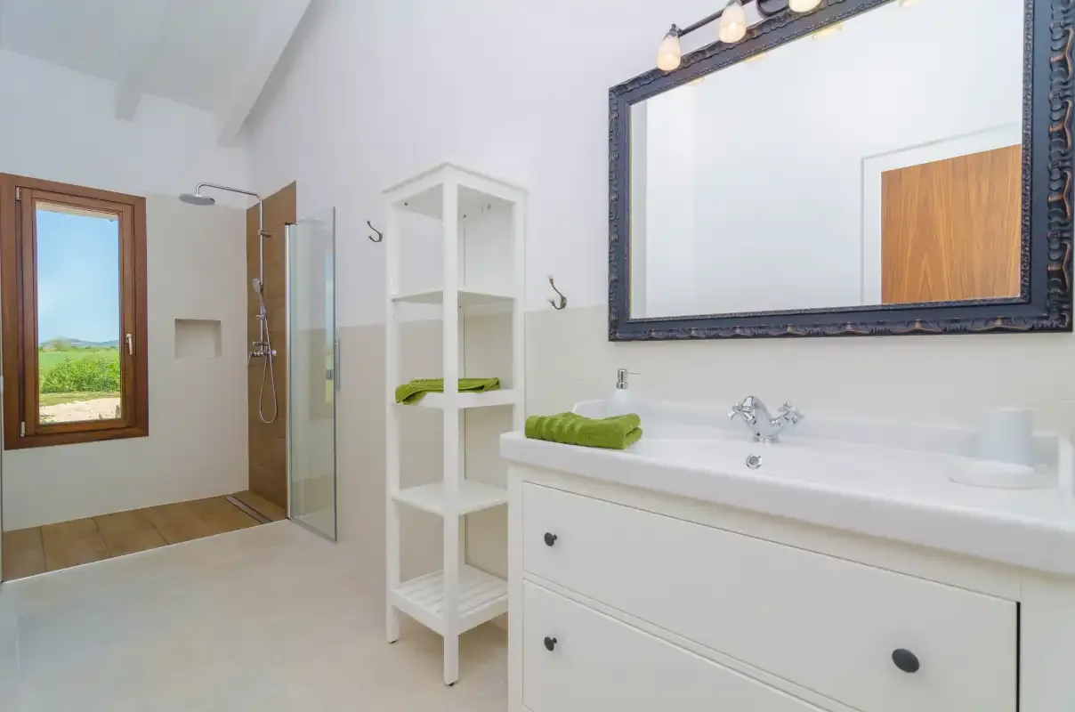A bright bathroom with a vanity, mirror, and shower.