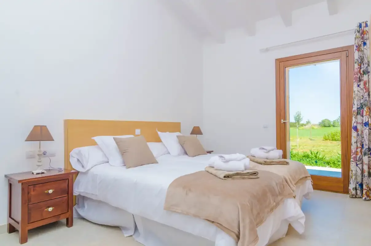 A bright bedroom with a neatly made bed beside a large window.