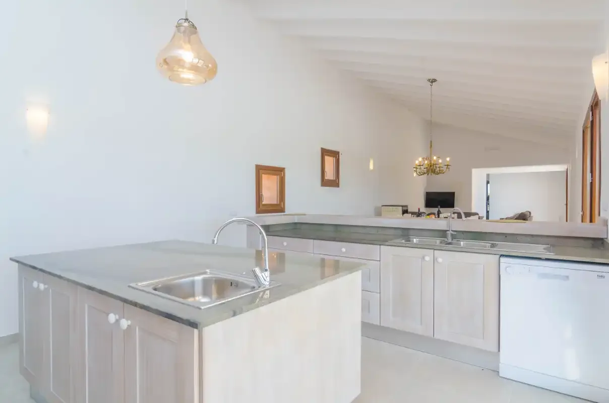 A bright kitchen with a central island and stainless-steel sink.