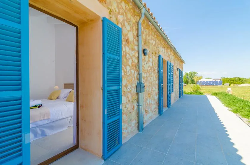 A stone building with bright blue shutters opens onto a paved walkway.
