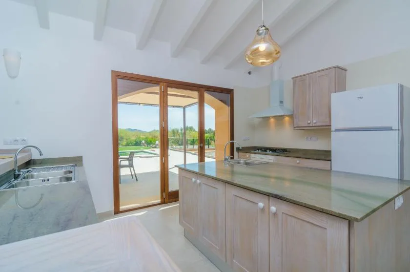A bright kitchen with a central island and glass doors opening onto a patio.