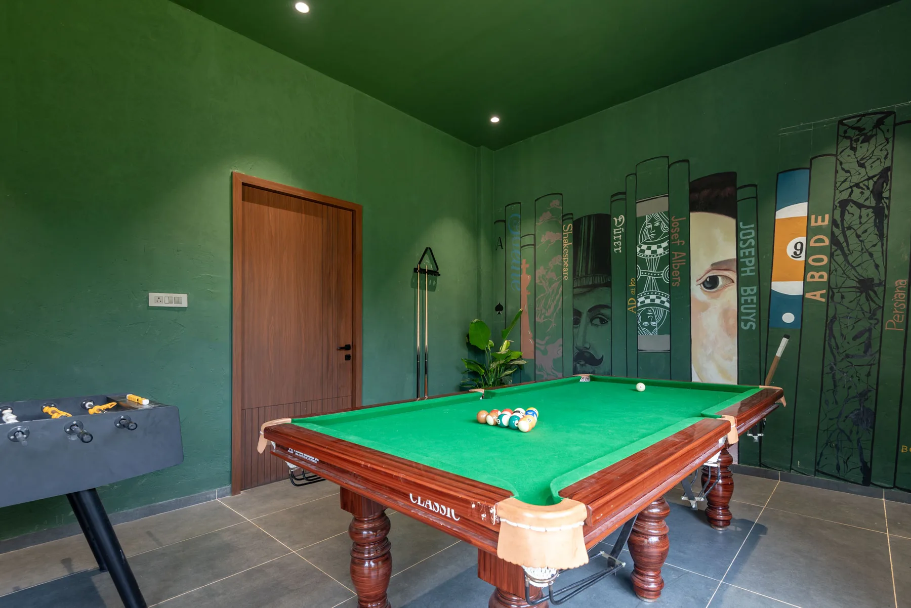 A game room with a green pool table and a foosball table.