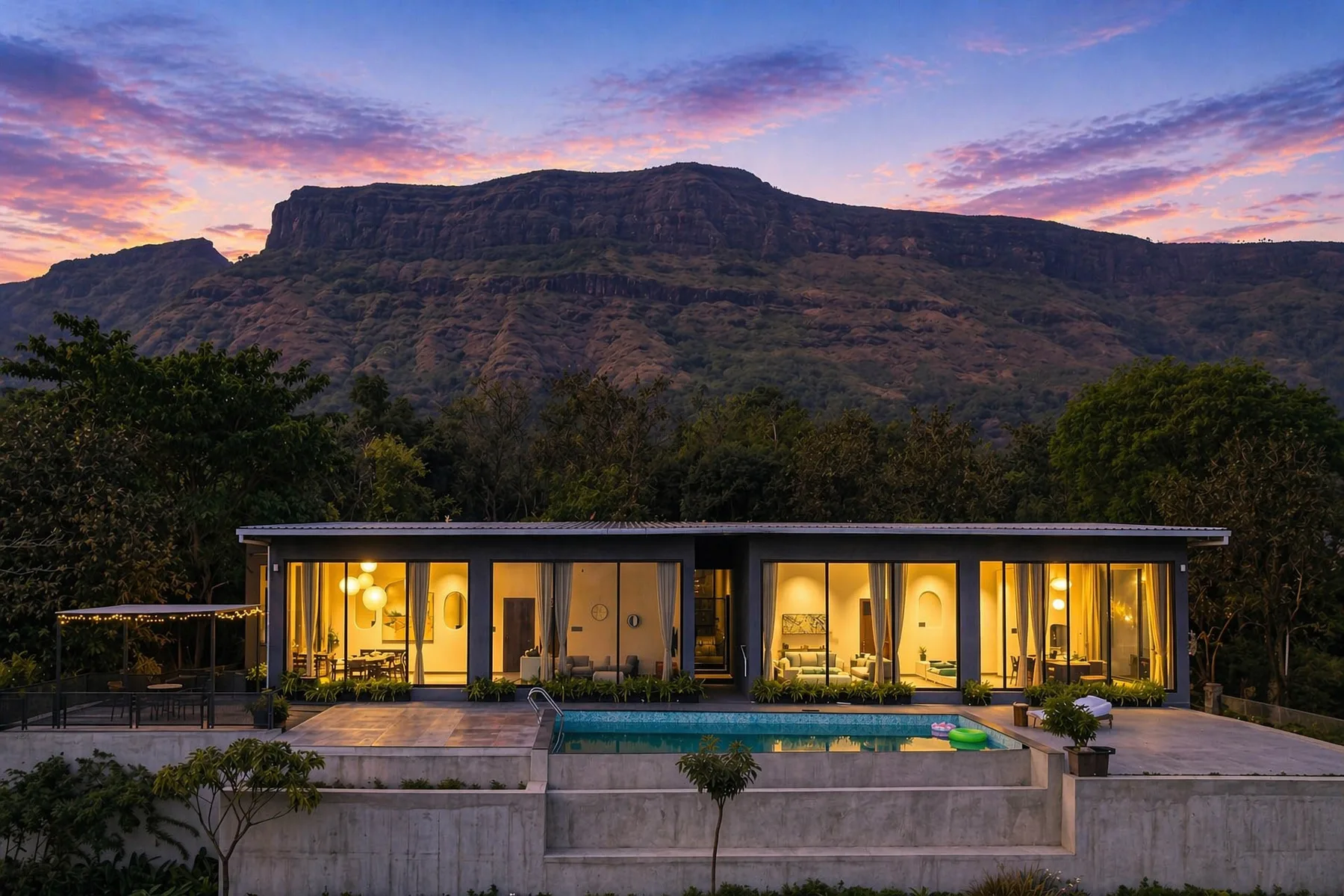 Una casa moderna con piscina se encuentra al pie de una montaña al atardecer.