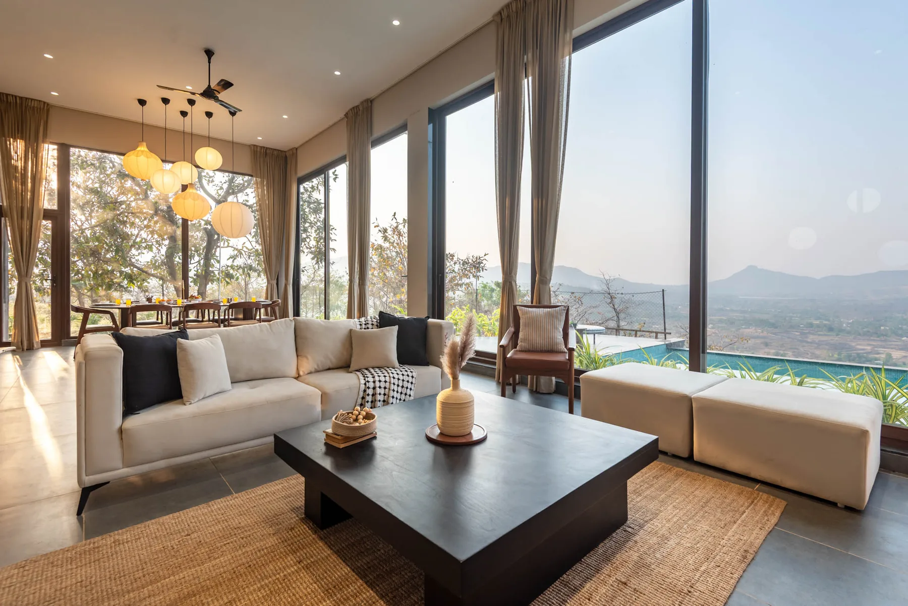 Una sala luminosa con asientos, una mesa de centro y grandes ventanales con vistas al paisaje.
