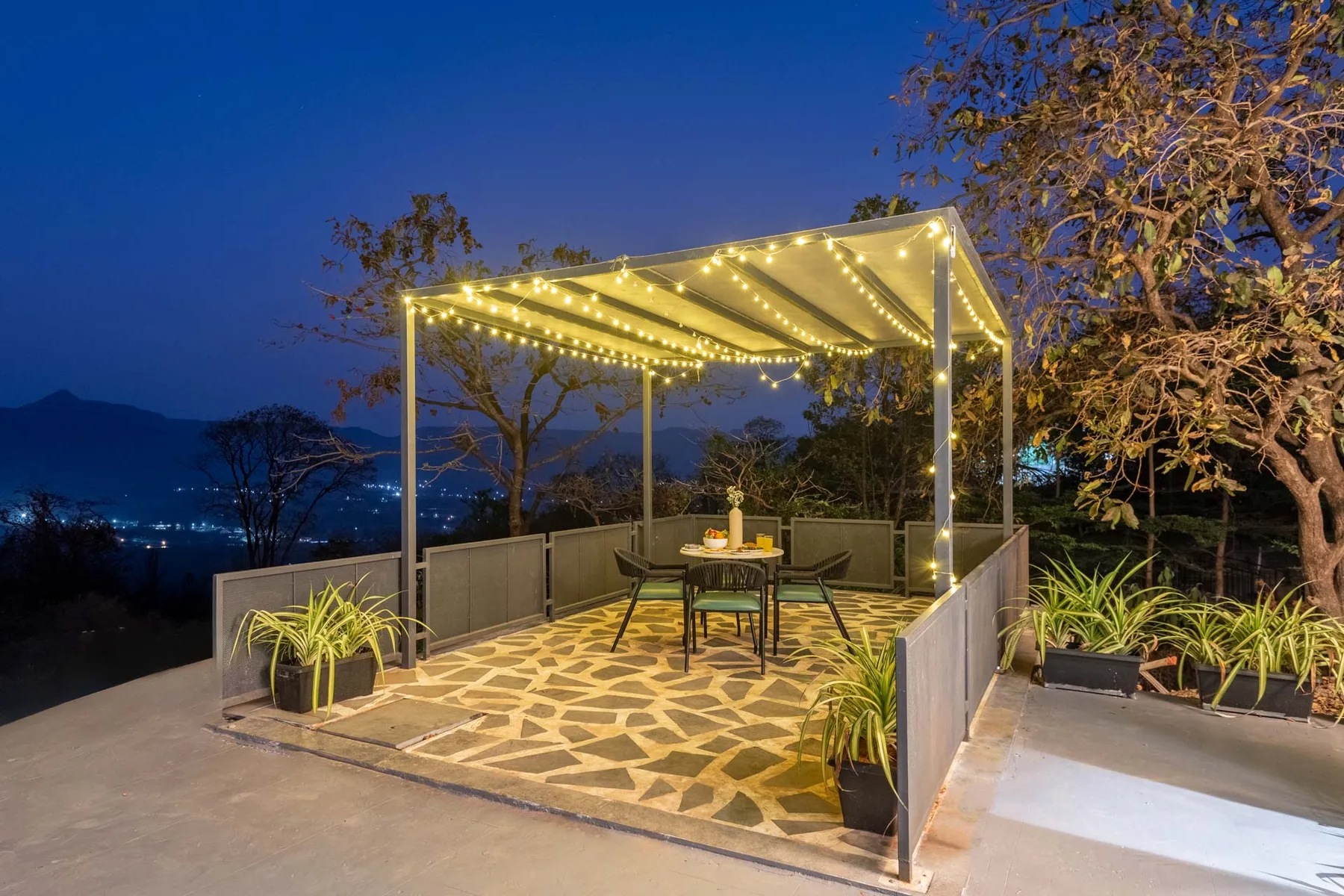 An outdoor terrace has a canopy strung with lights and a small table.