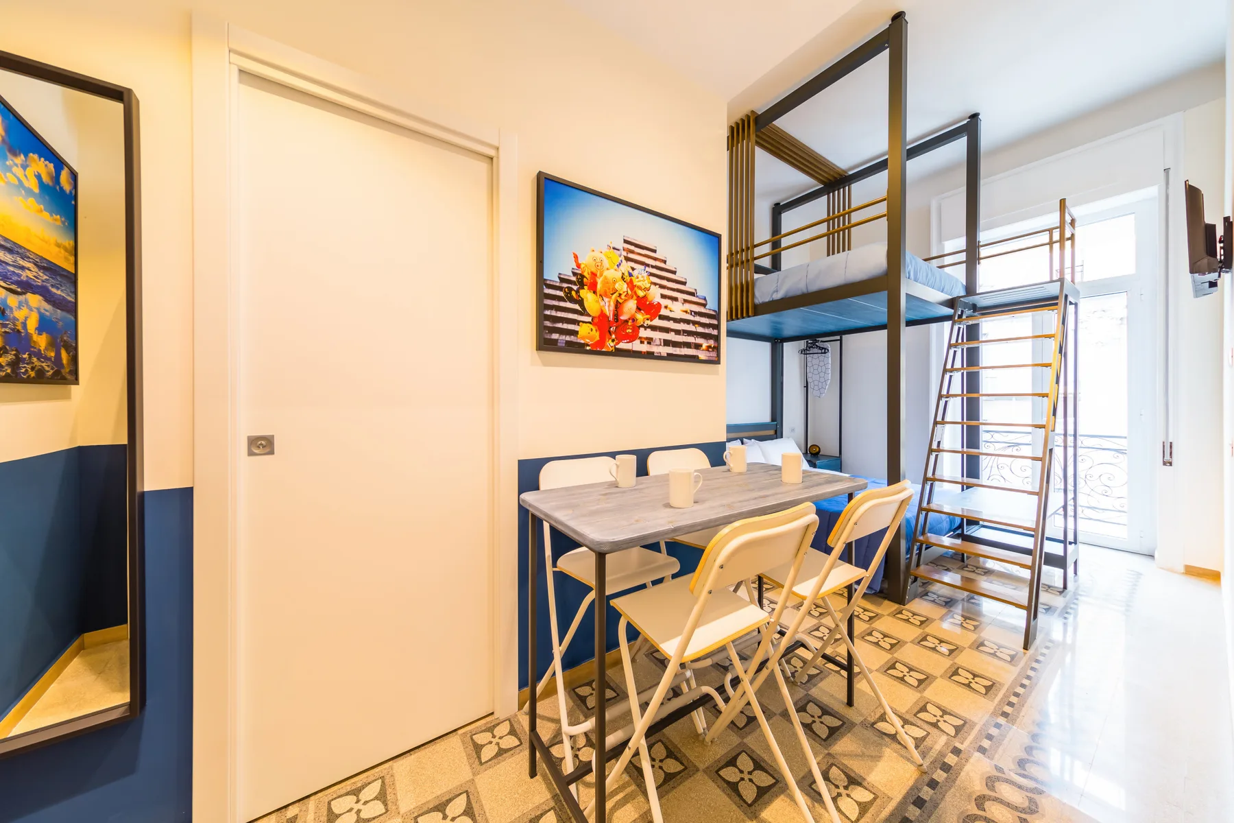 Un pequeño comedor con mesa y sillas está bajo una cama elevada.