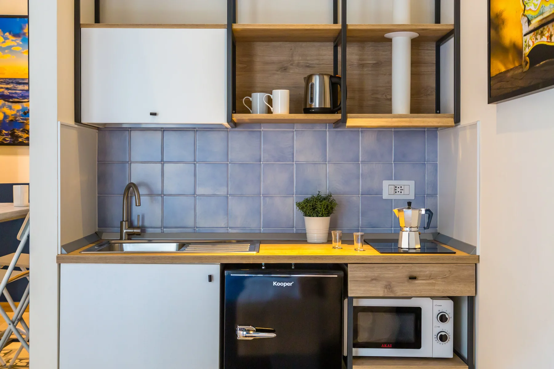A compact kitchen with a tiled backsplash, sink, and countertop appliances.