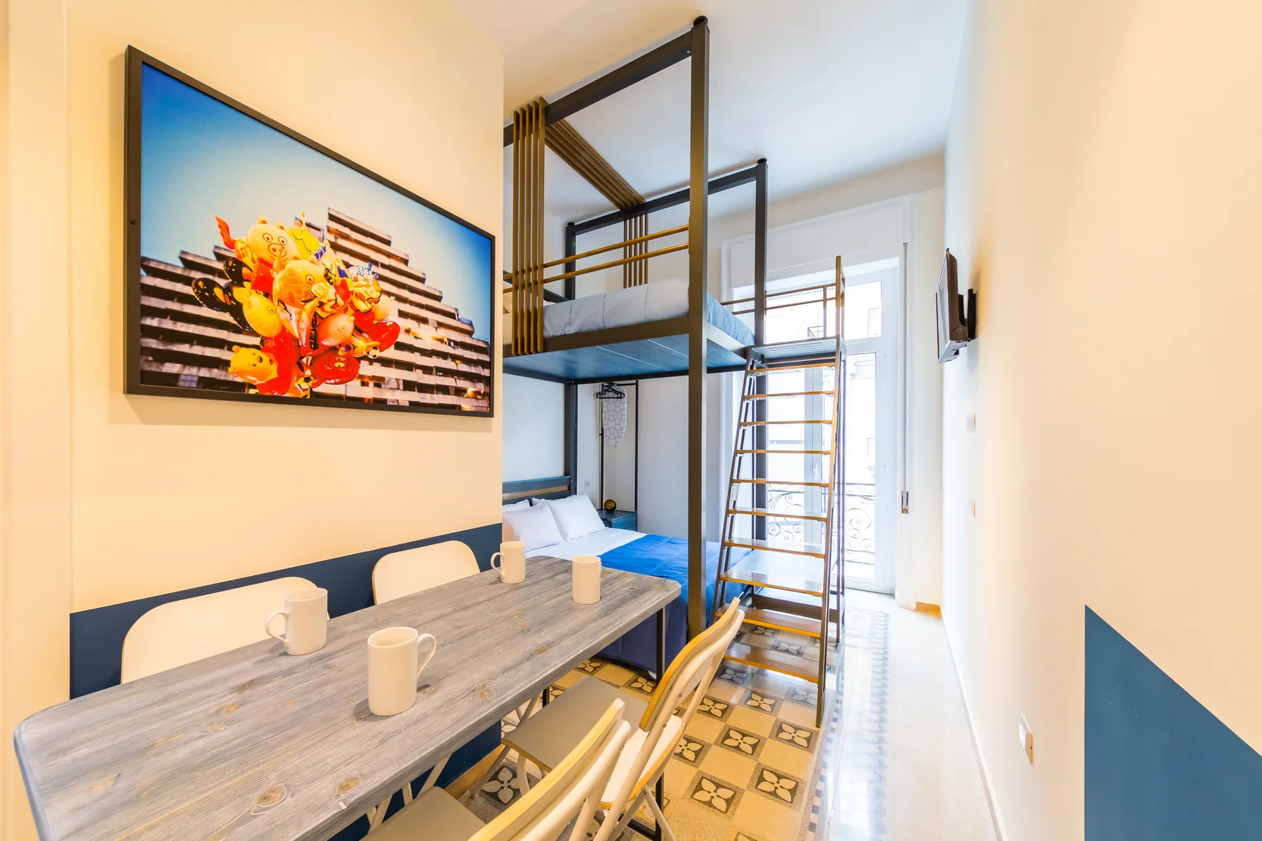 Un dormitorio luminoso con una litera, una mesa y arte en la pared.
