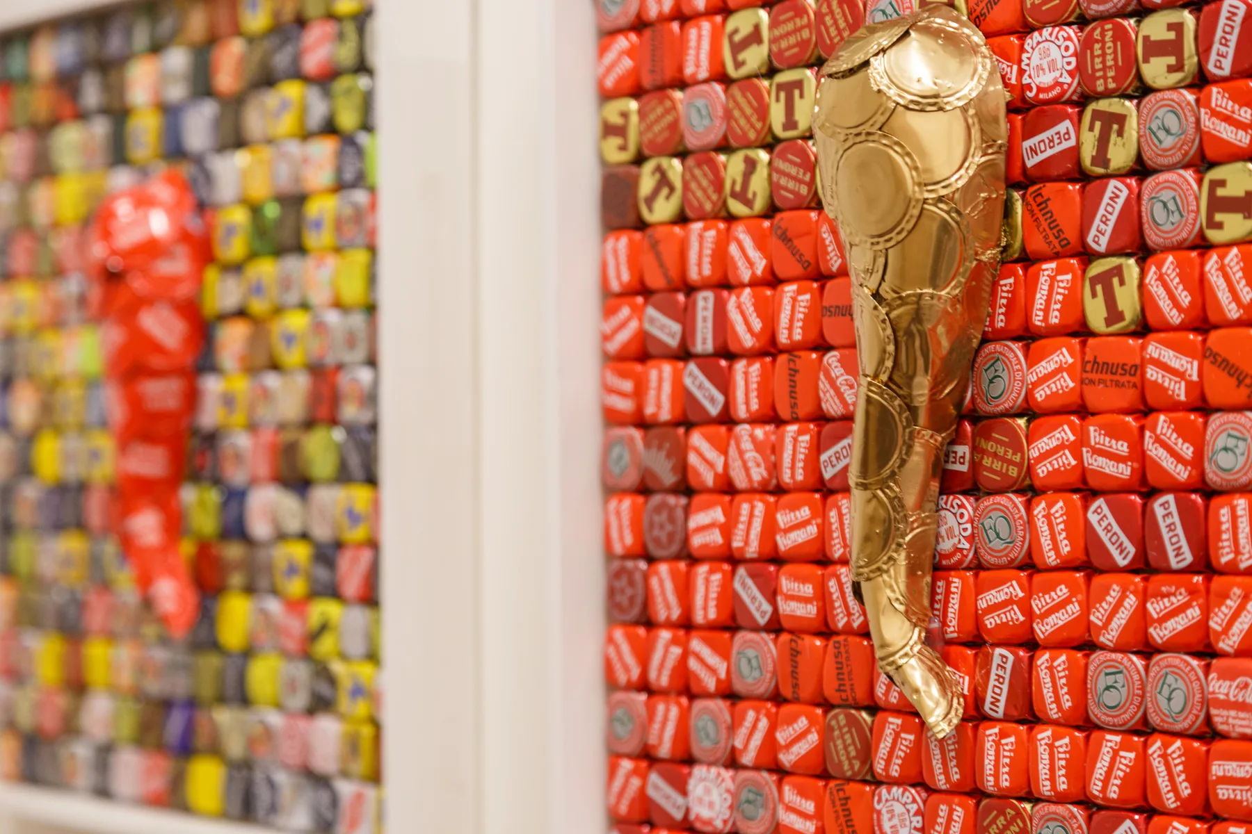 A gold-colored trophy hangs against a wall covered in red cans.