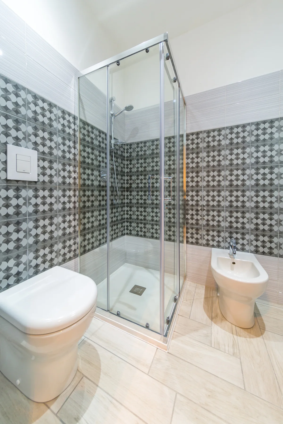 A bathroom with a glass shower, toilet, and bidet.
