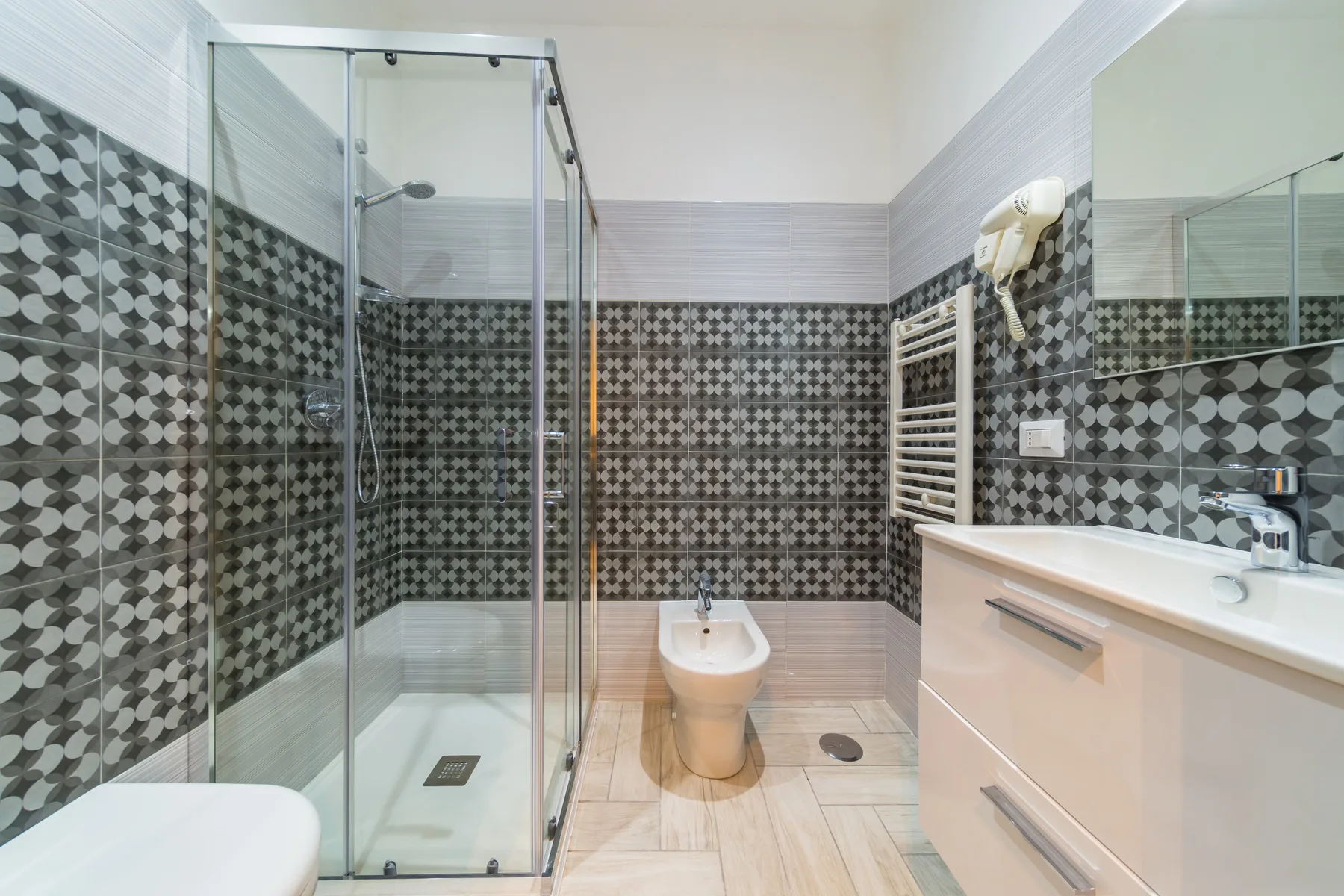 A modern bathroom with a glass shower, toilet, and sink.