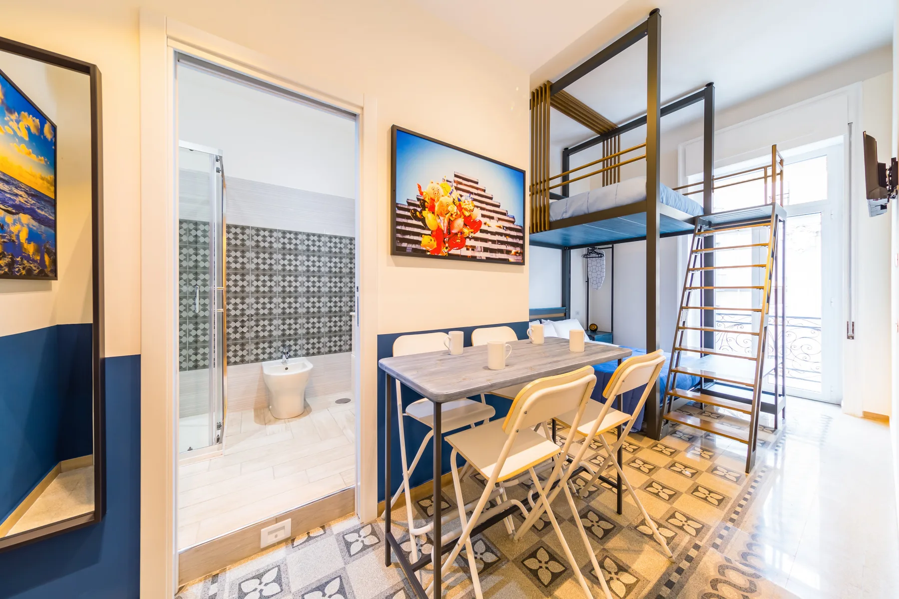 Dormitorio con mesa de comedor y literas junto a un baño abierto.