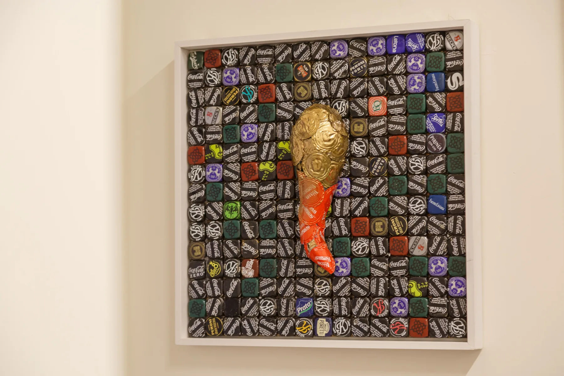 A framed artwork displays a gold and red figure against a patterned background.