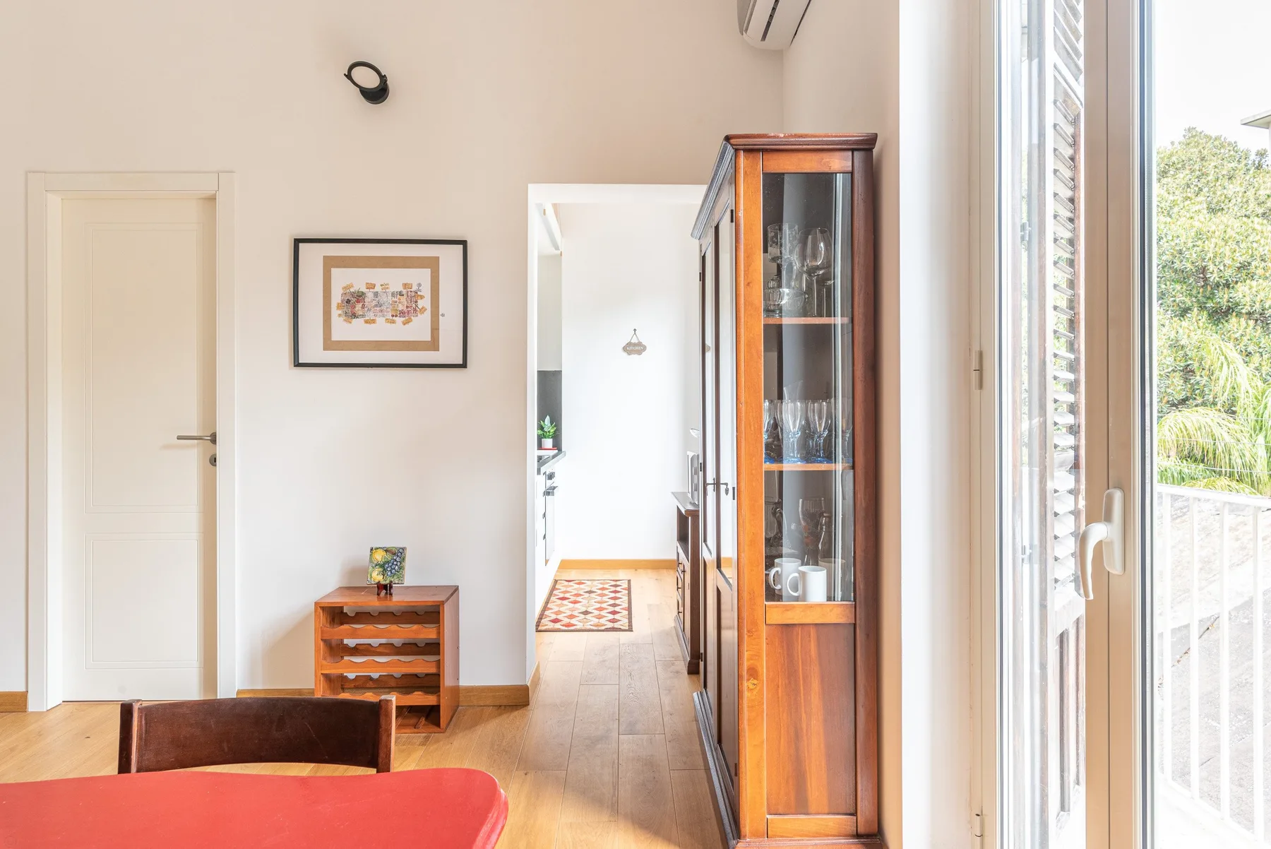 Una sala luminosa con una vitrina y grandes ventanas.