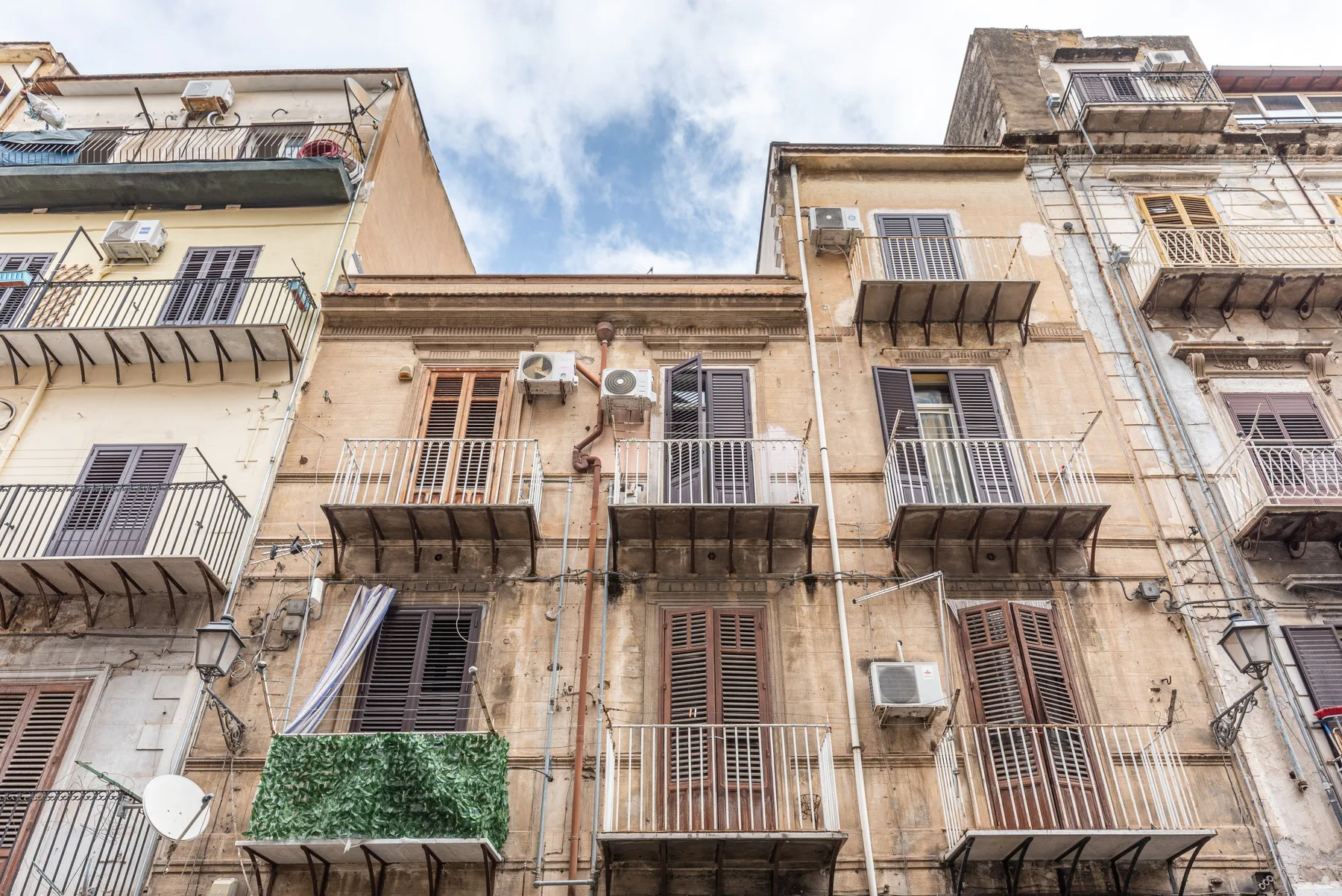 Una hilera de edificios de apartamentos envejecidos con balcones bajo un cielo nublado.