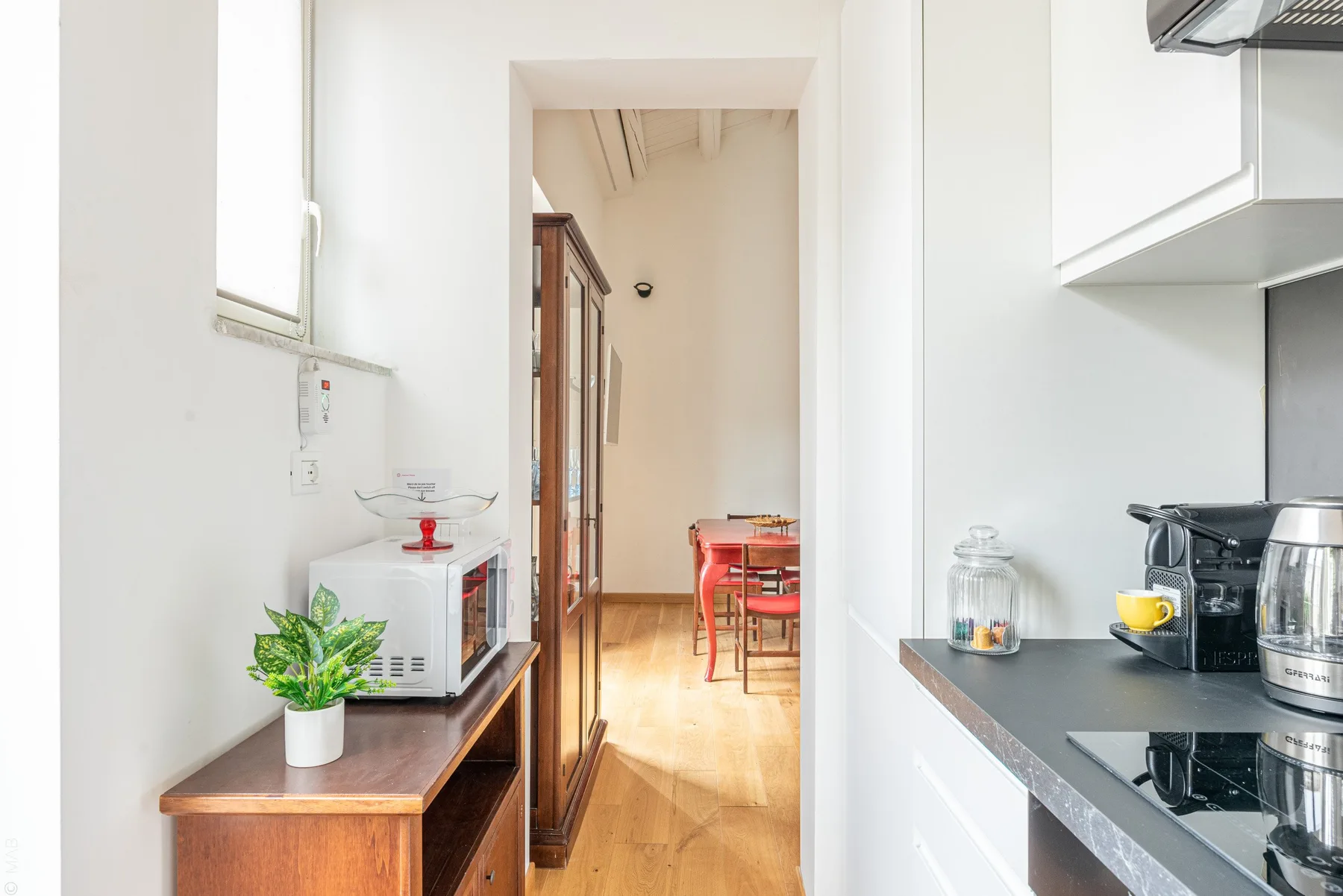 Una cocina luminosa se abre a un comedor con una mesa y sillas.