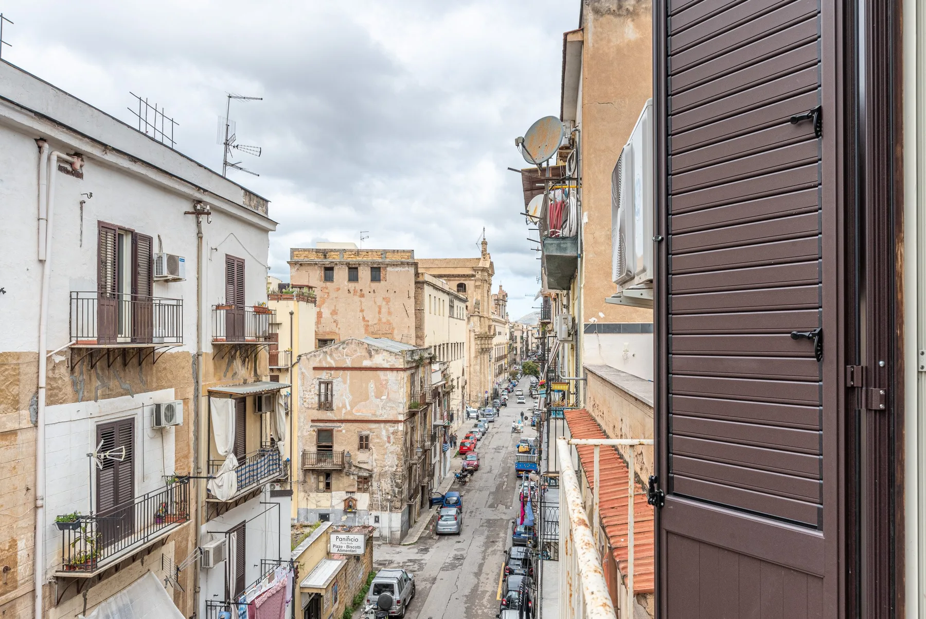 Una calle estrecha está flanqueada por edificios muy juntos y balcones.